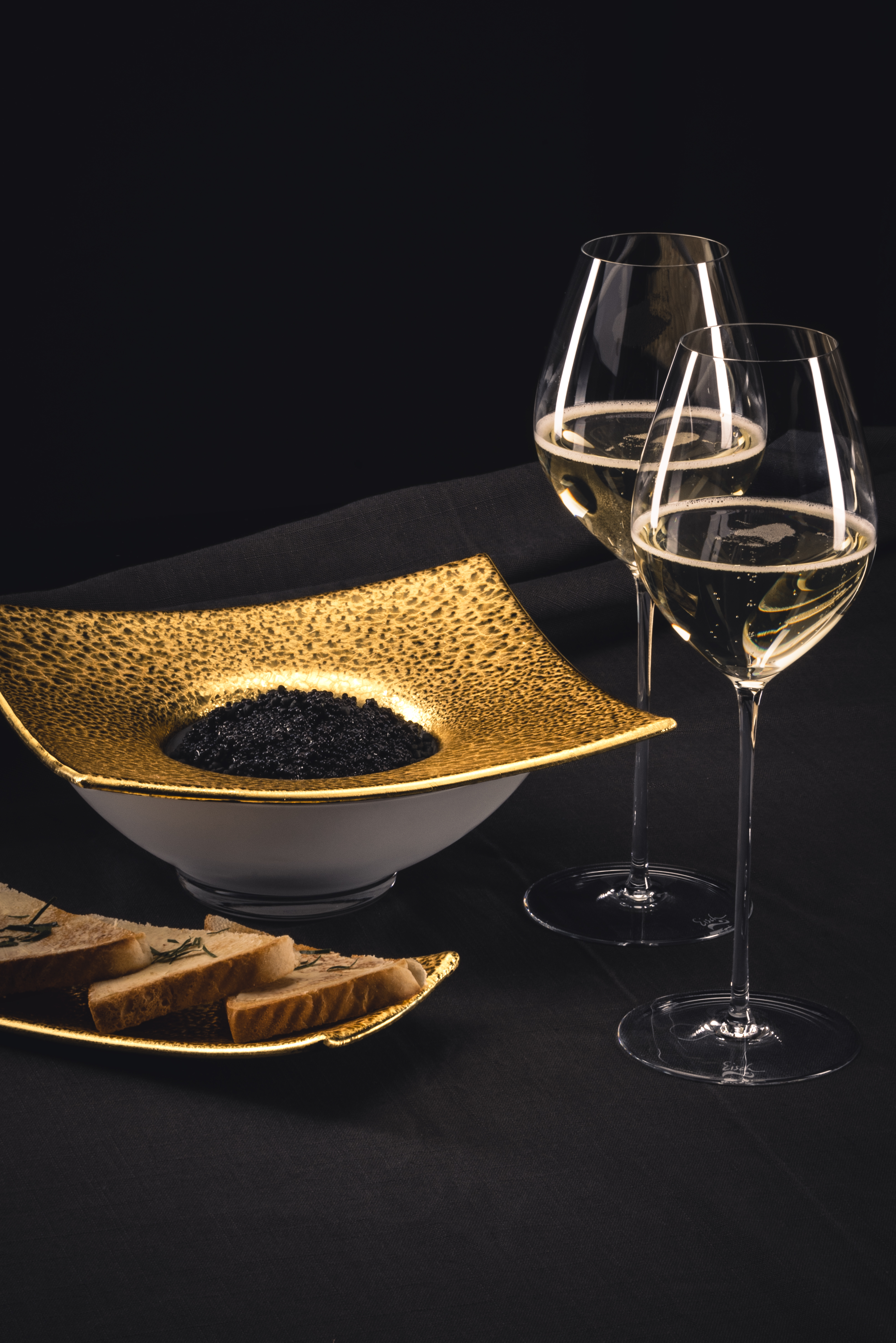 Two champagne glasses with golden caviar dish on a table