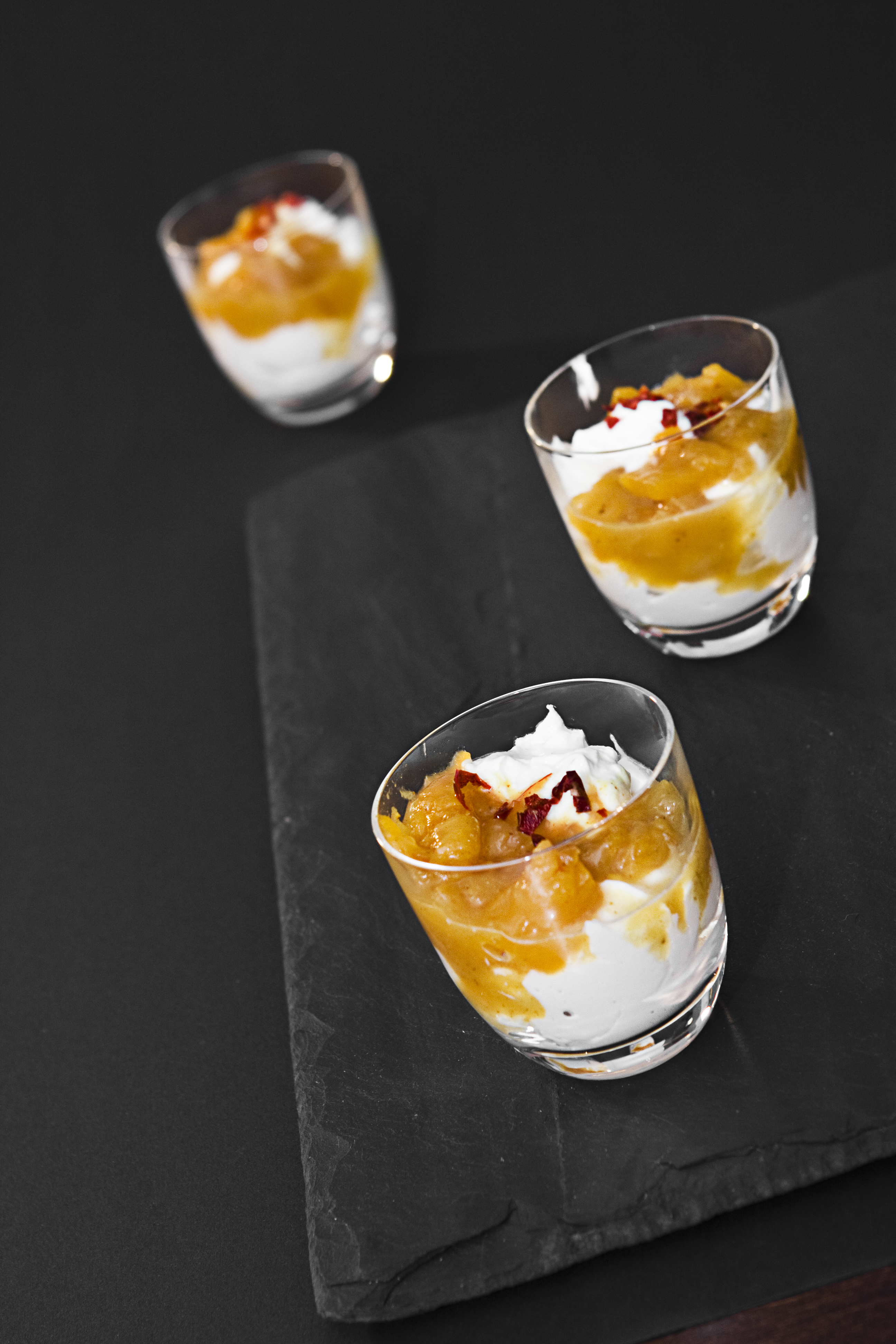 4 befüllte Dessertgläser auf schwarzem Tisch