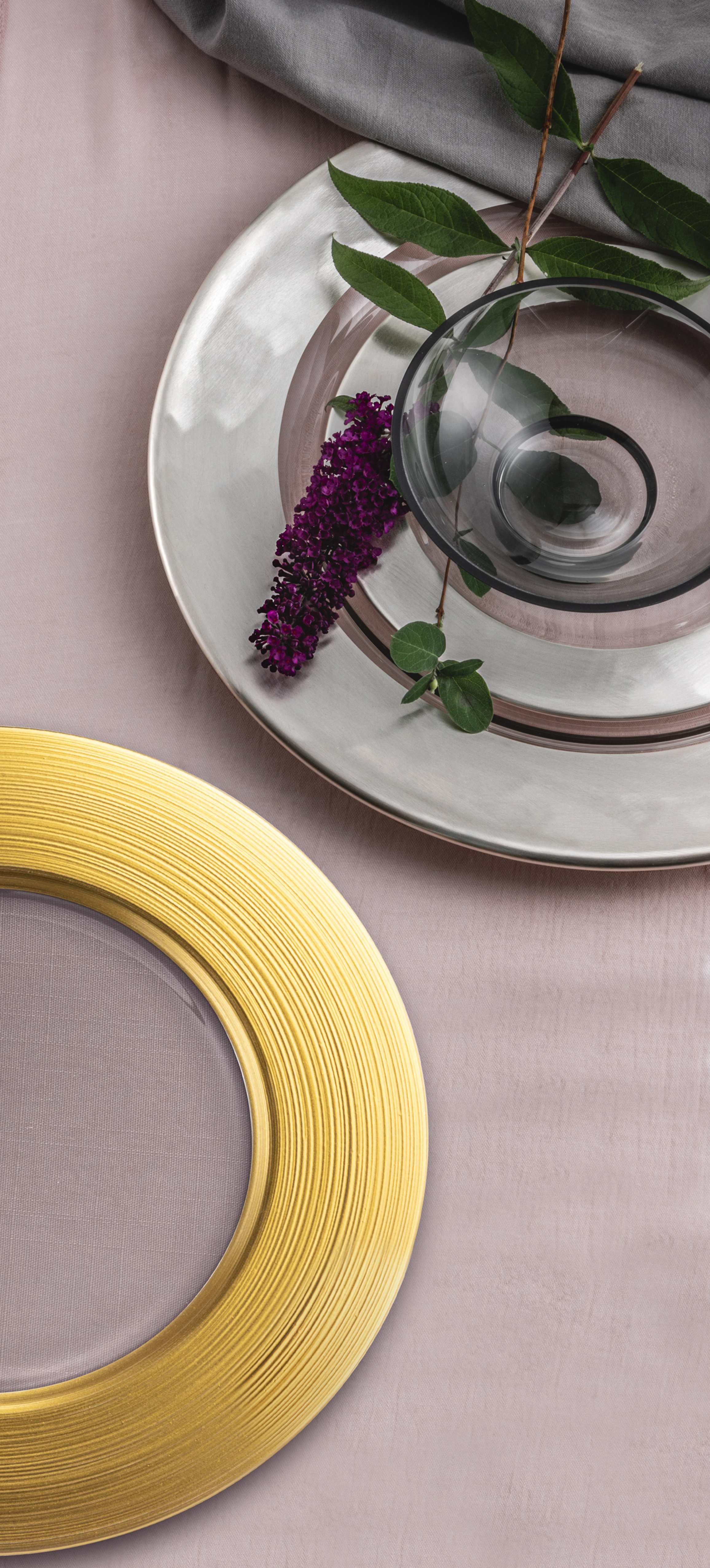 Plates in gold and silver with purple lilacs on table