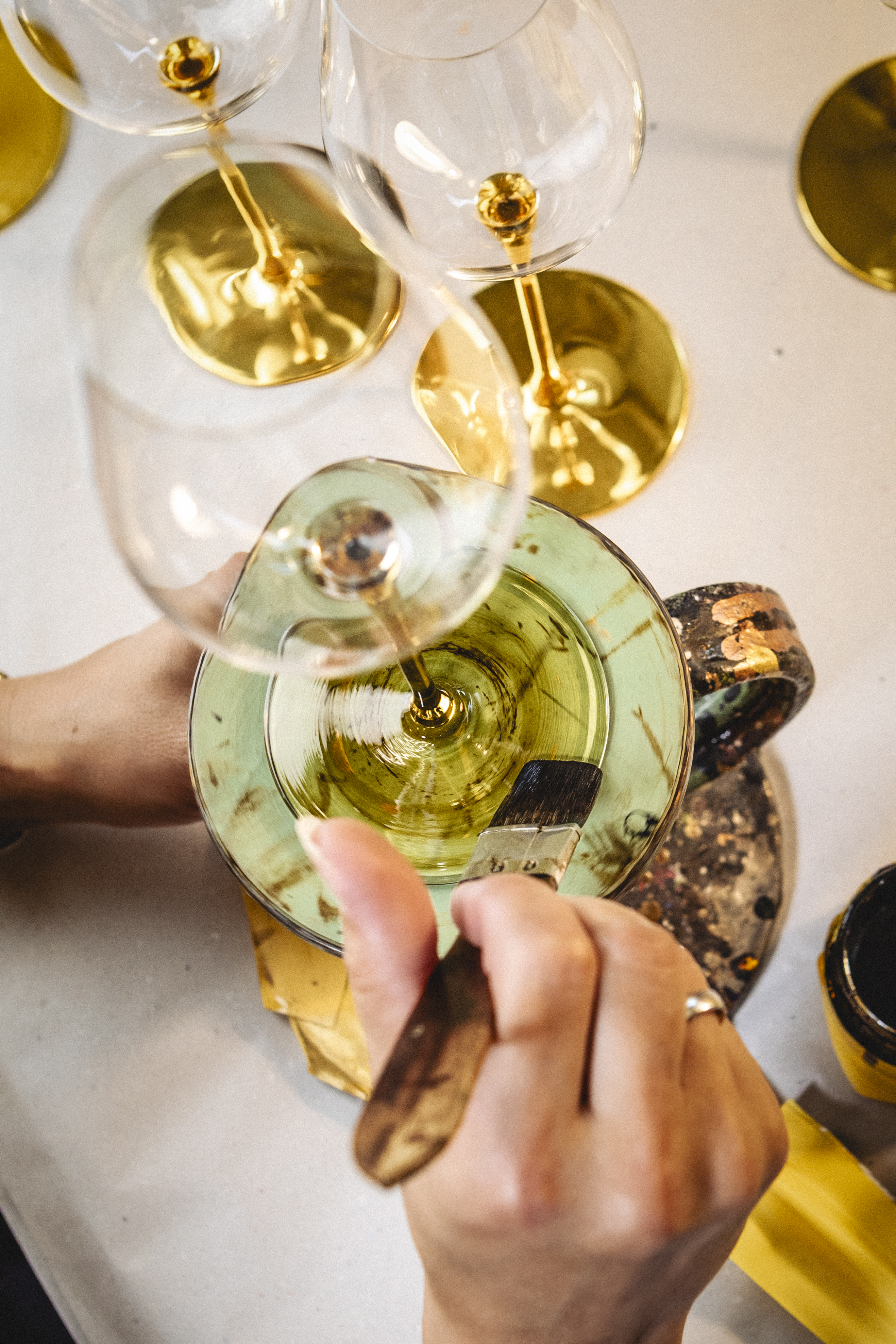 Hands painting a glass with gold paint using a brush