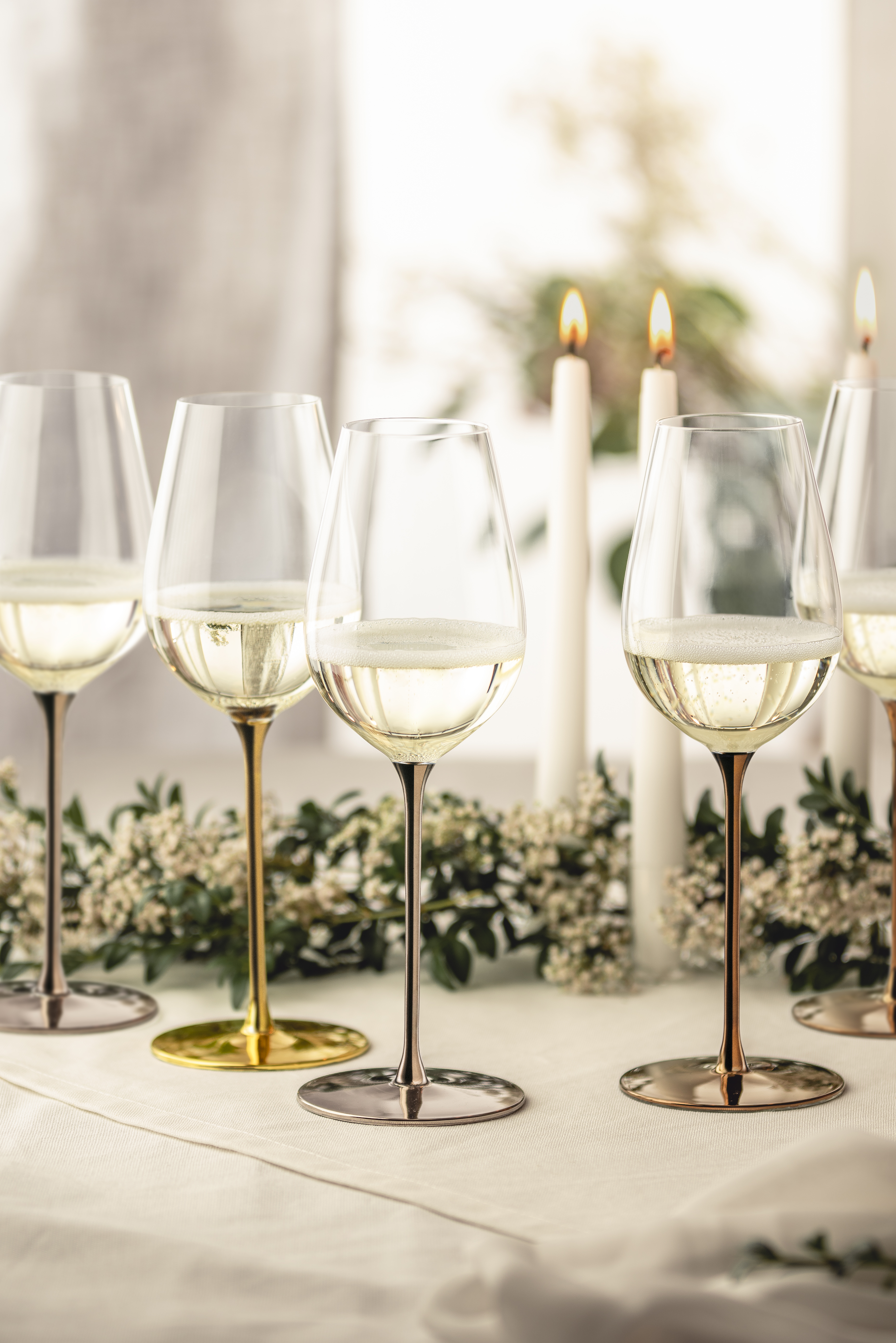 Four white wine glasses in precious metal colours