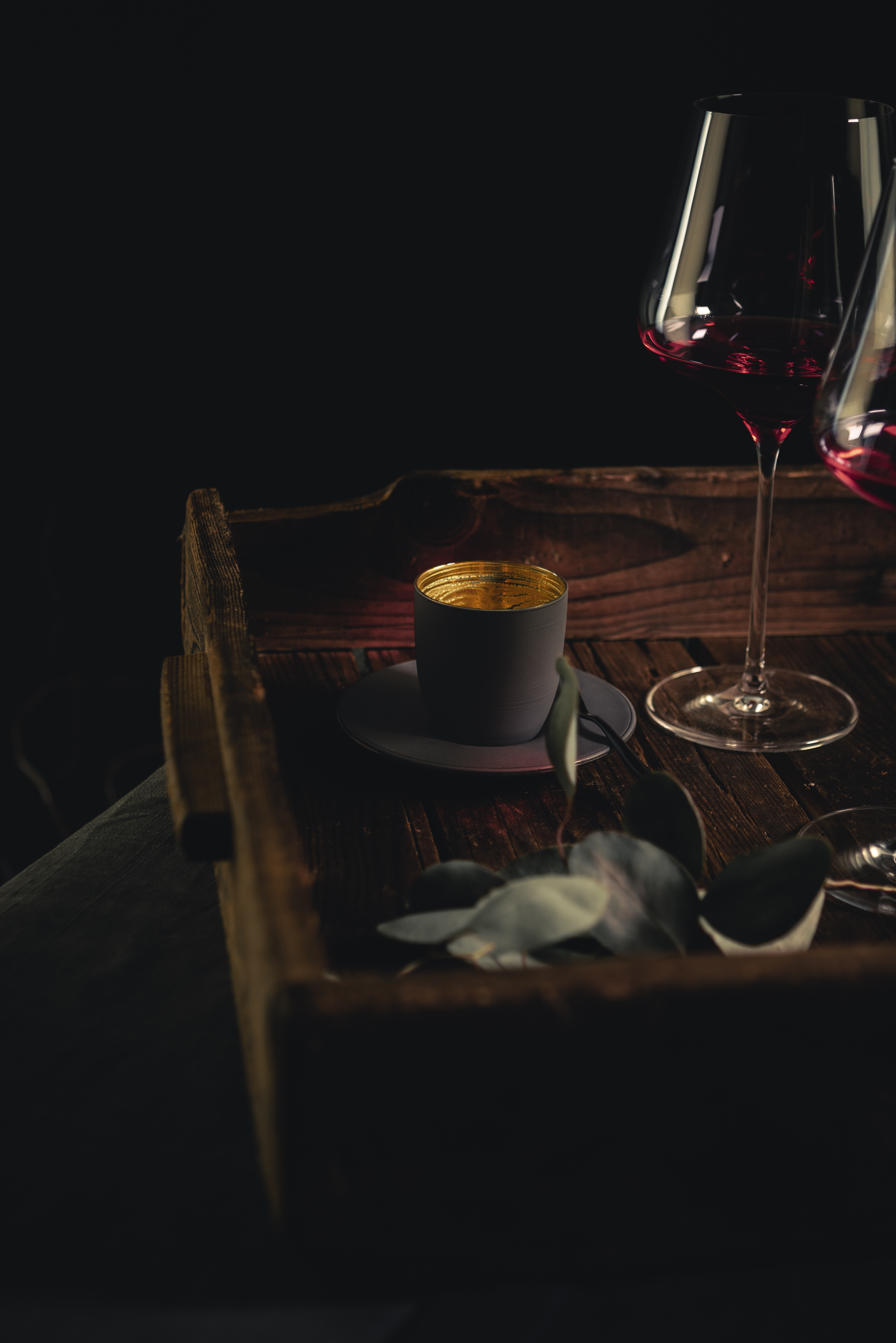 Black and gold espresso glass with red wine glasses on a wooden tray