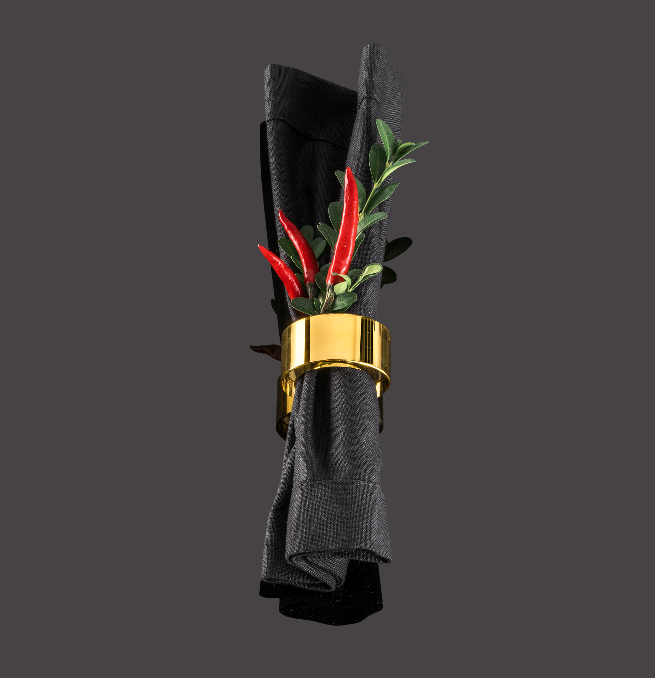 Gold napkin ring with black napkin and red pods
