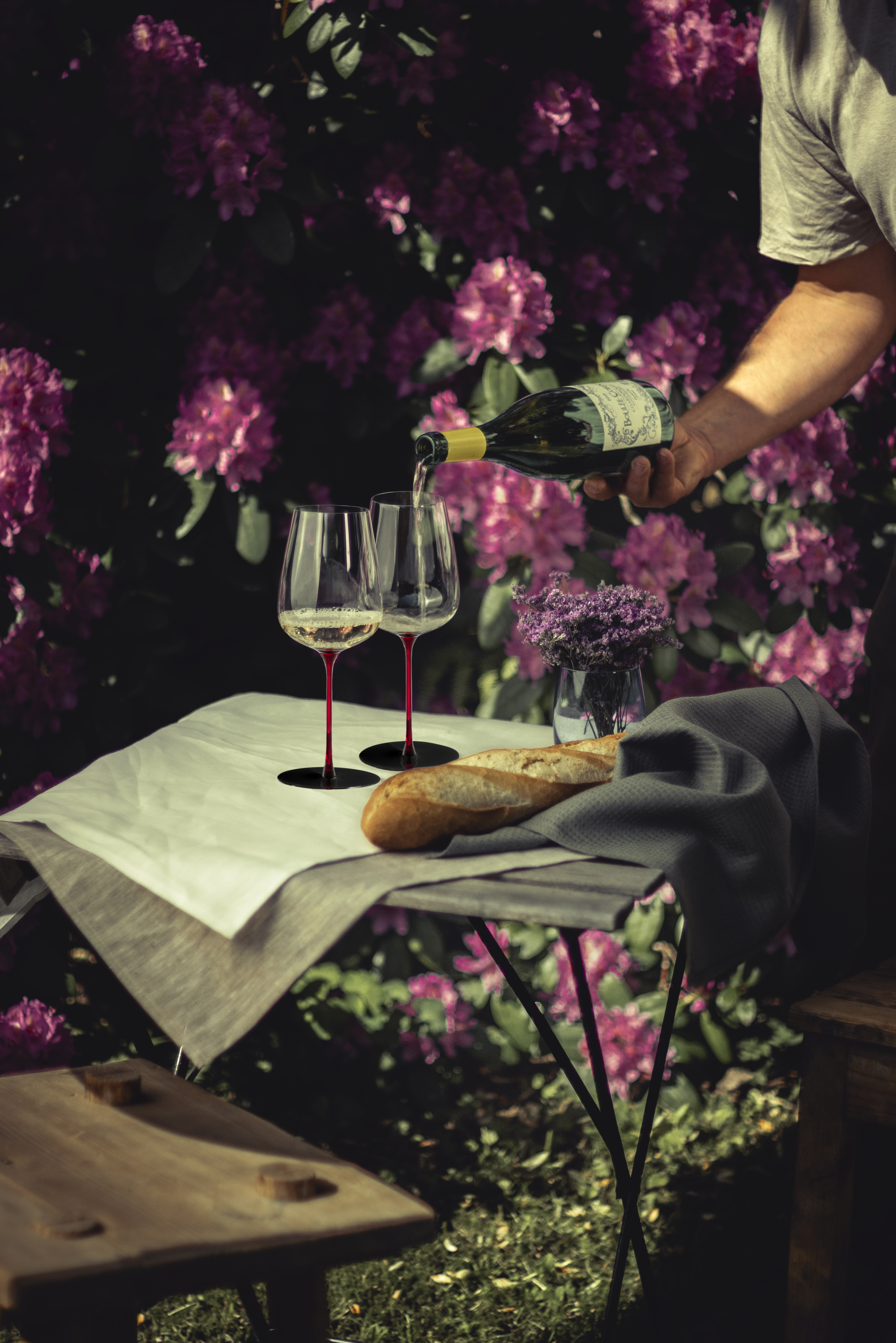 Two red-stemmed wine glasses among pink flowers