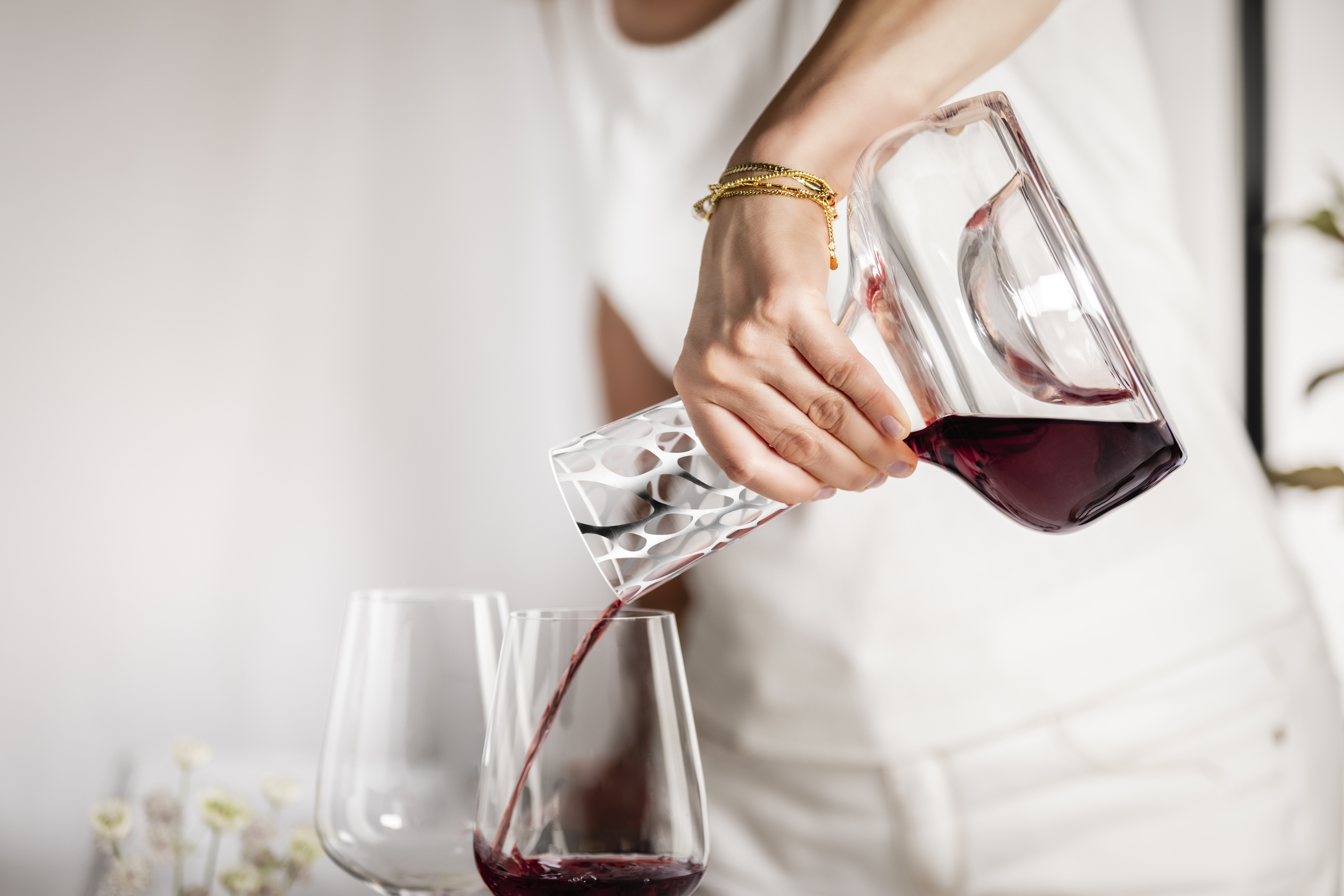 A person pours red wine from a decanter from the Net series into a glass