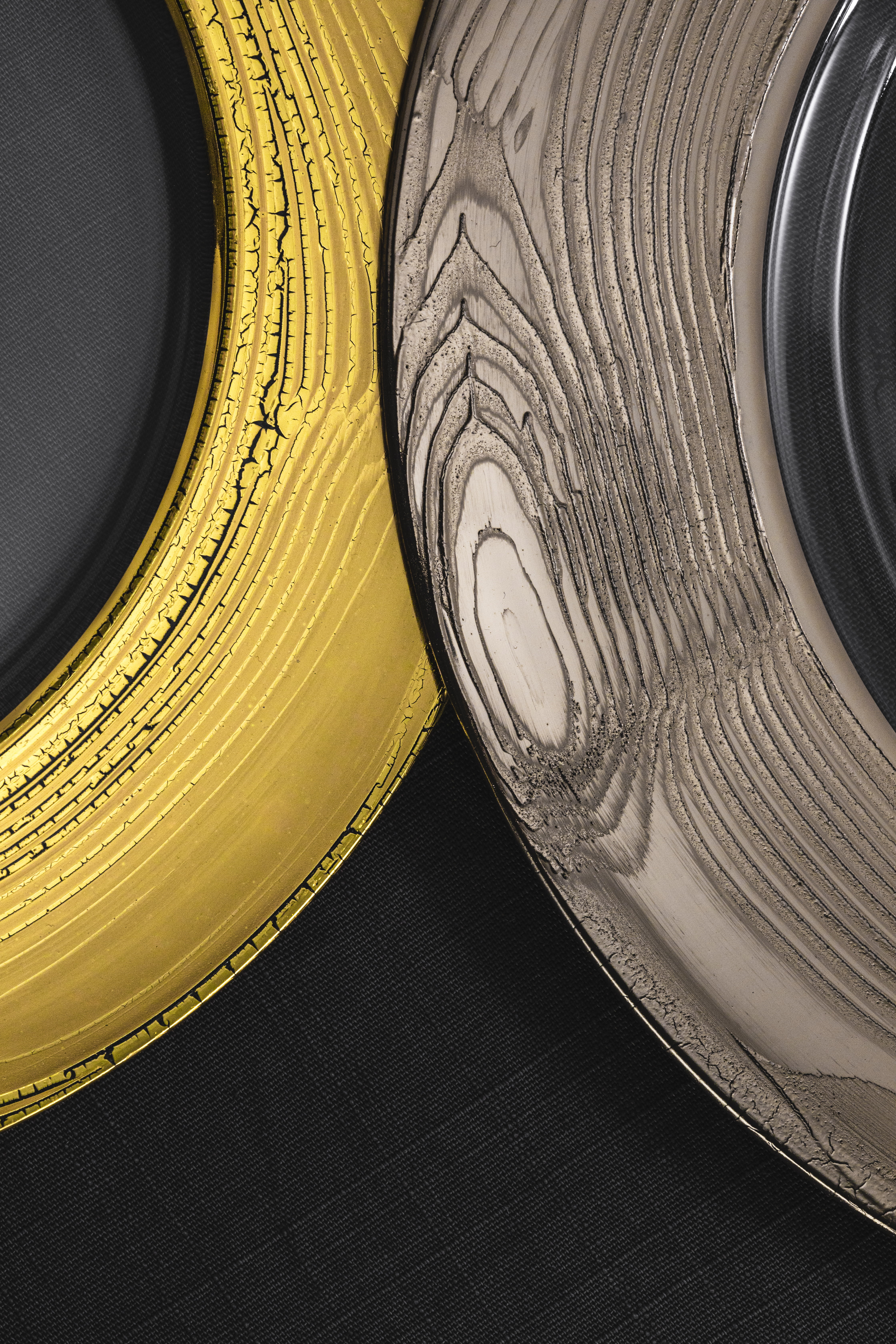 Golden and platinum-coloured plate rims in front of a dark background