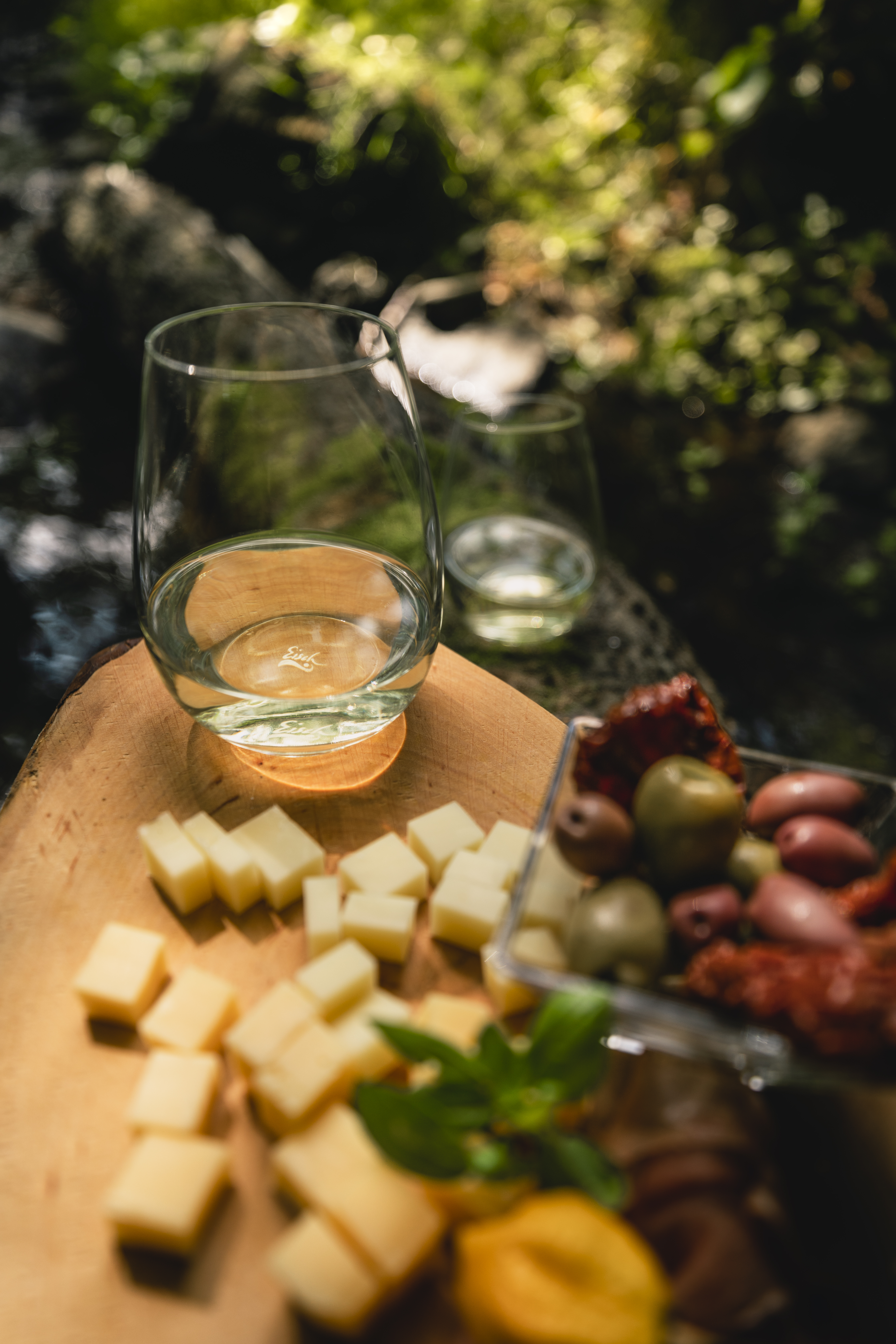 A cup stands on a board with cheese and antipasti