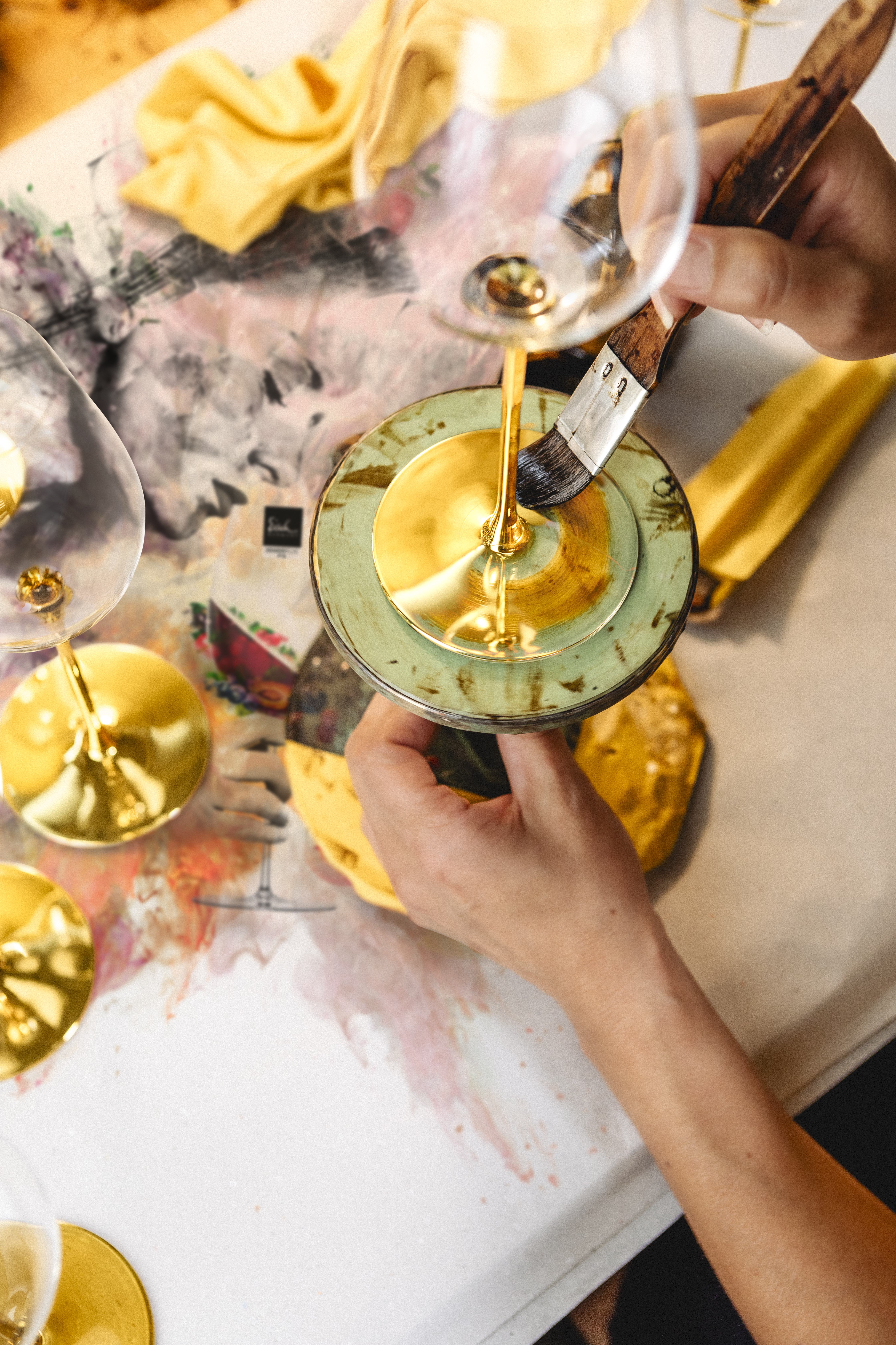 Hands painting a glass with gold