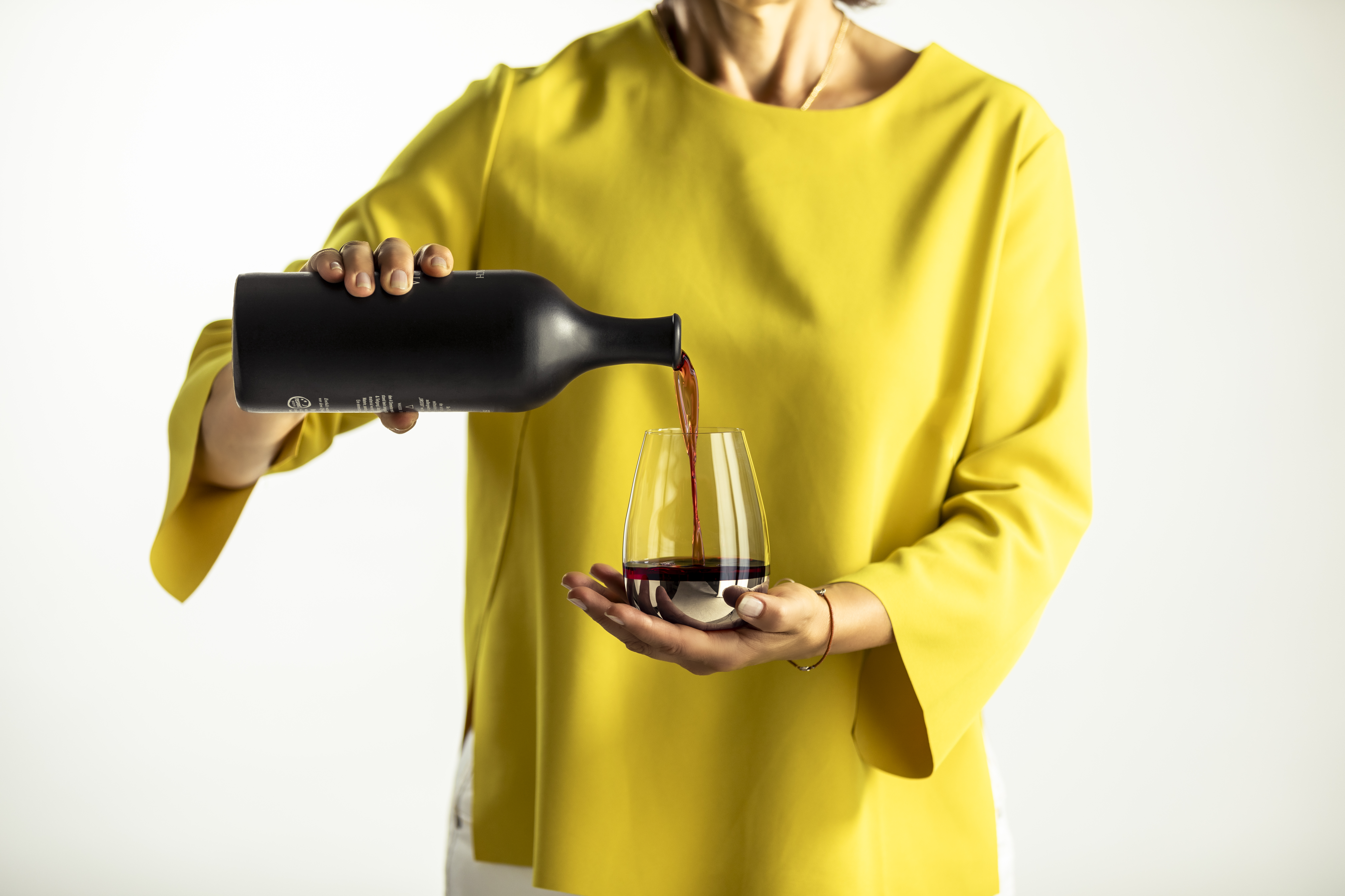 A person pours wine into a platinum-coloured glass from the Elevate series.