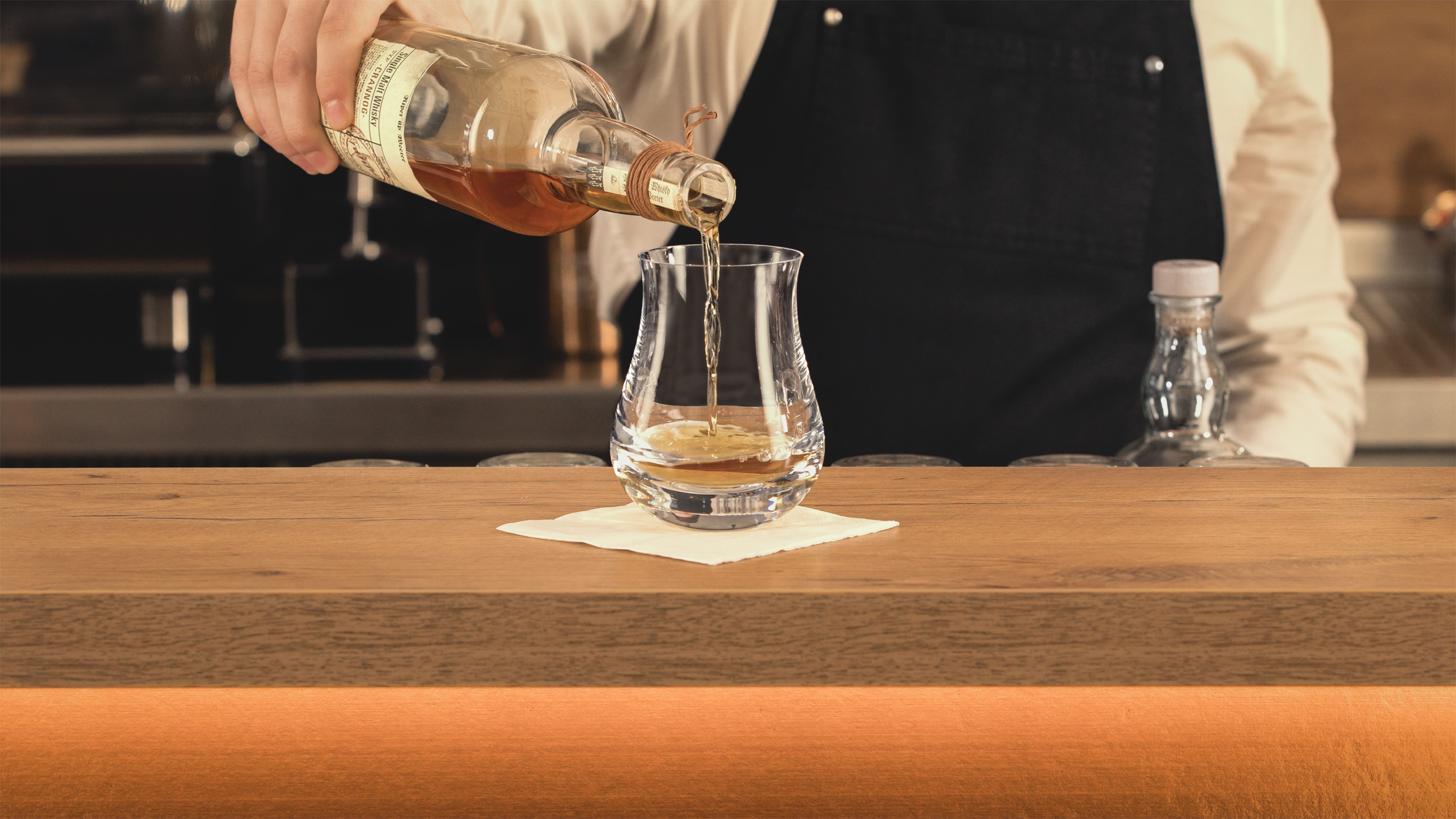 Barkeer gießt Whisky in Gentleman Whiskygläser