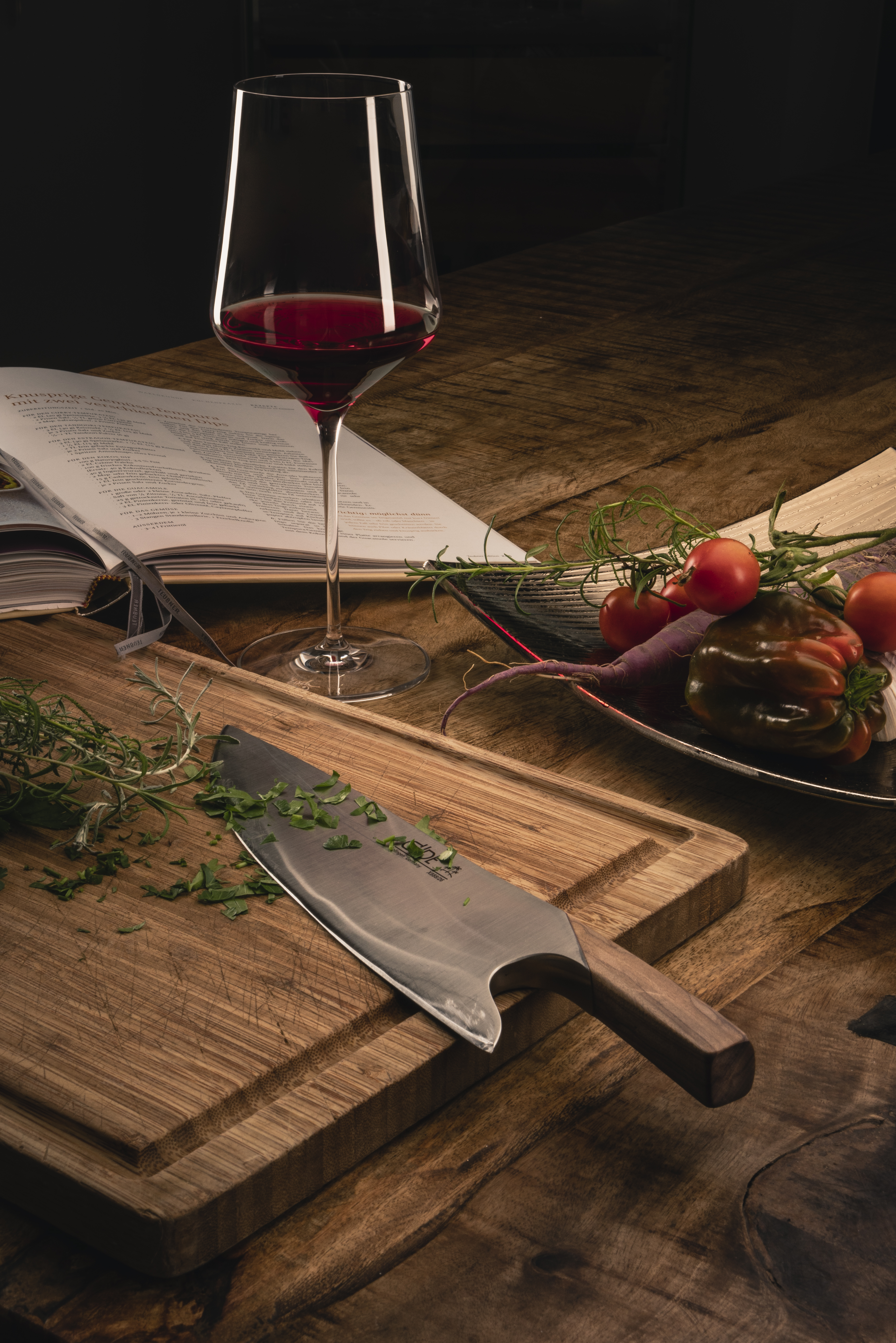 Wine glass between cookbook and chopping board
