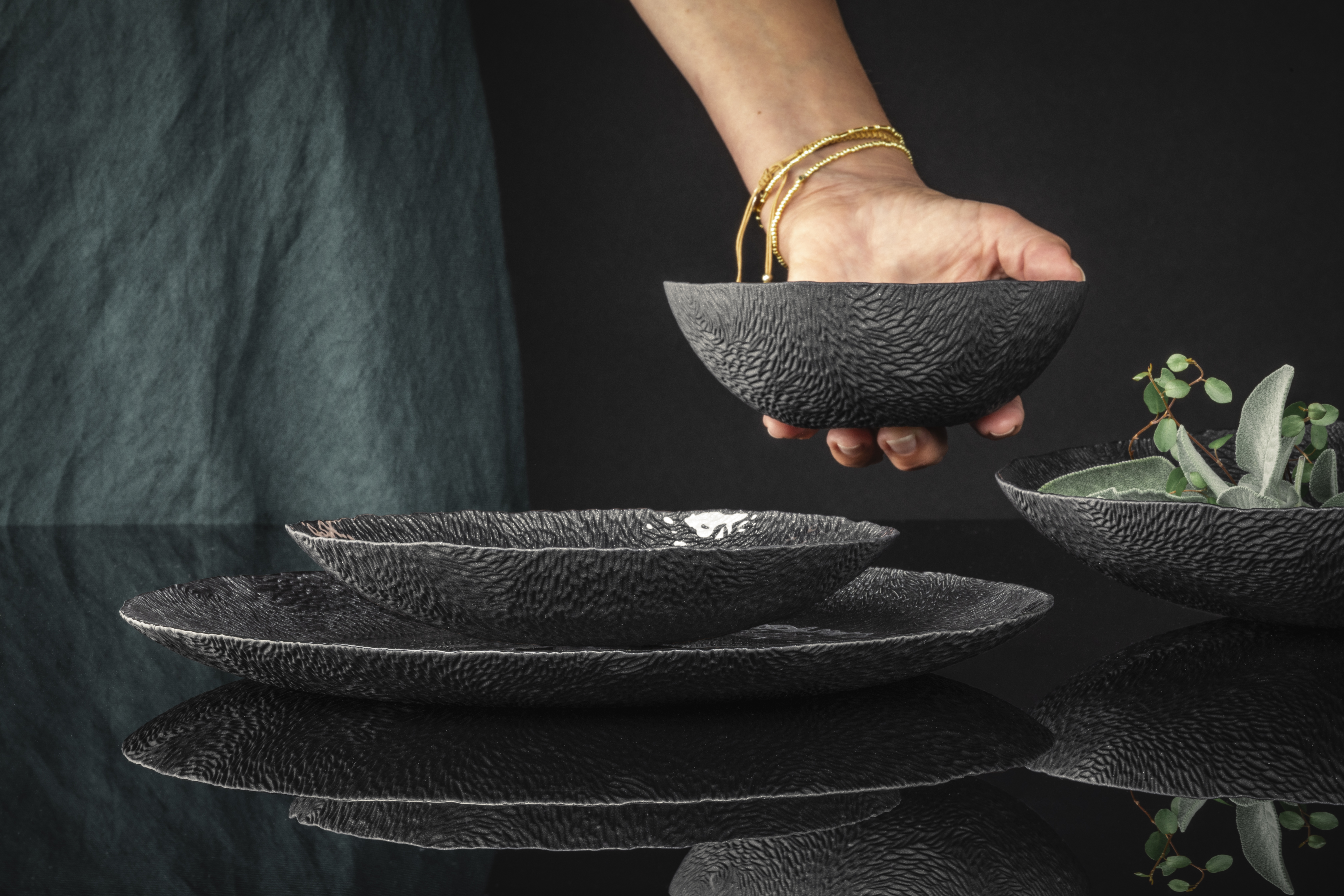 Eine Hand stellt eine schwarze Schale zu den anderen auf den Tisch