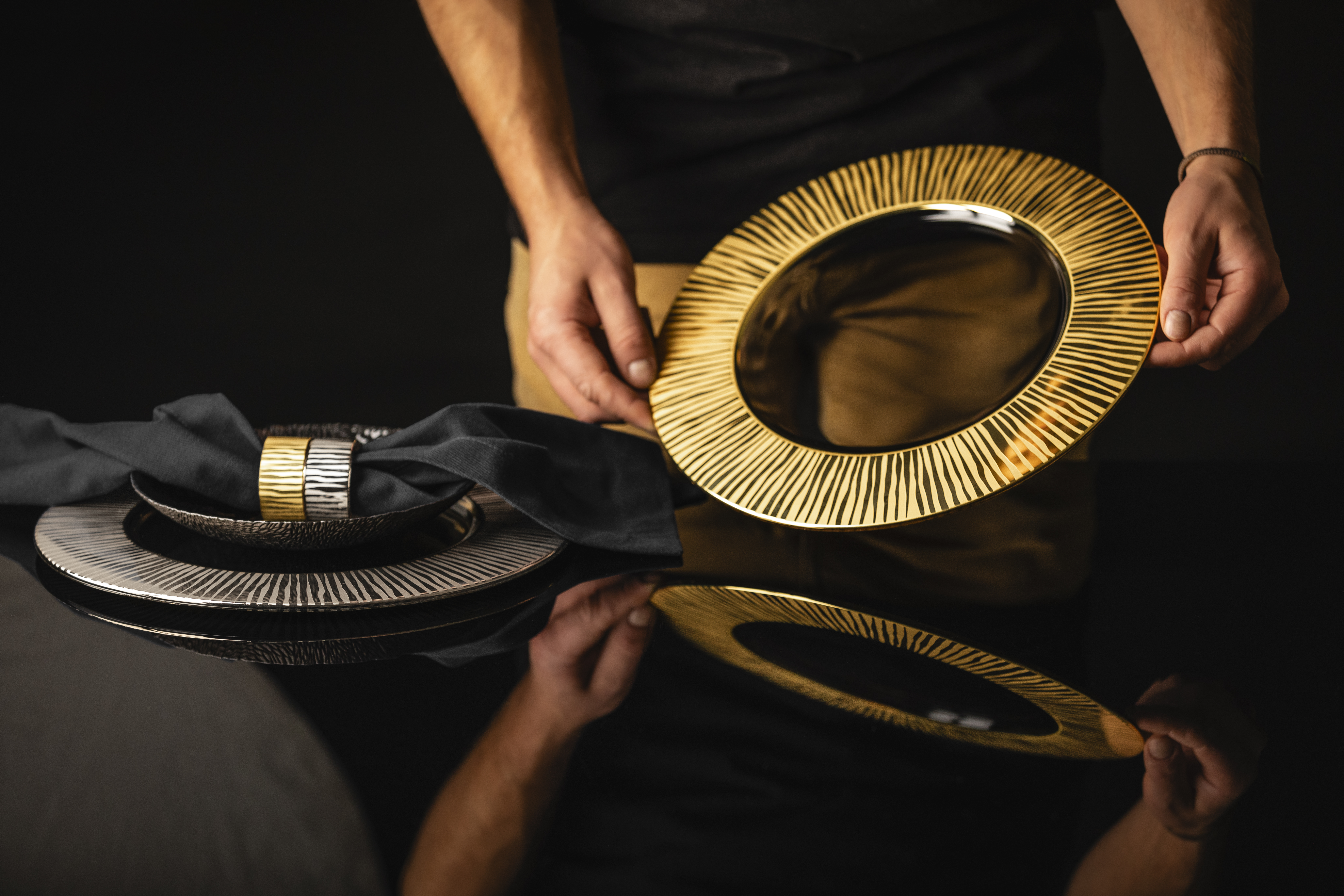 Hände stellen goldenen Teller auf Tisch