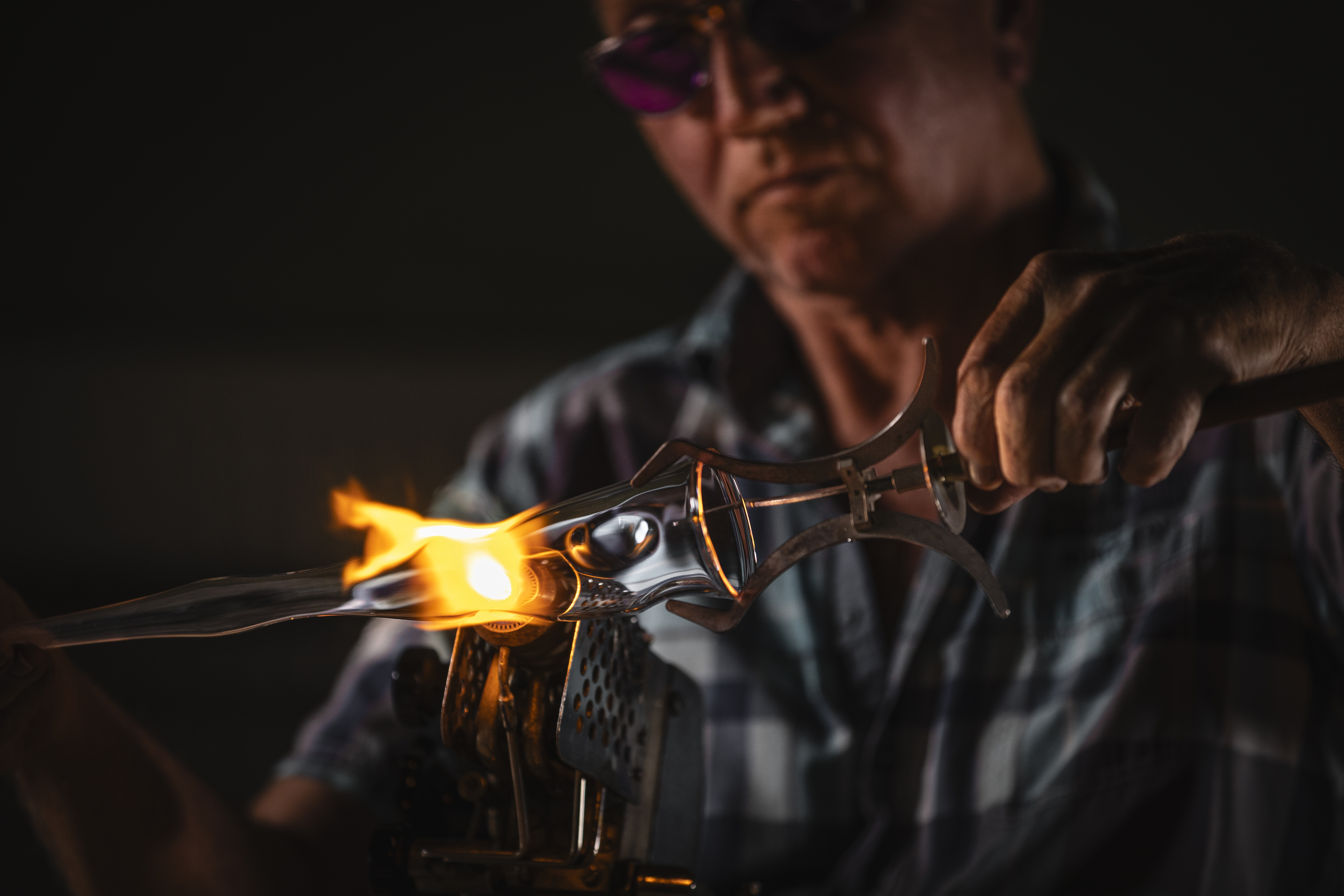 Glassmaker shaping Unik mugs in front of an open flame