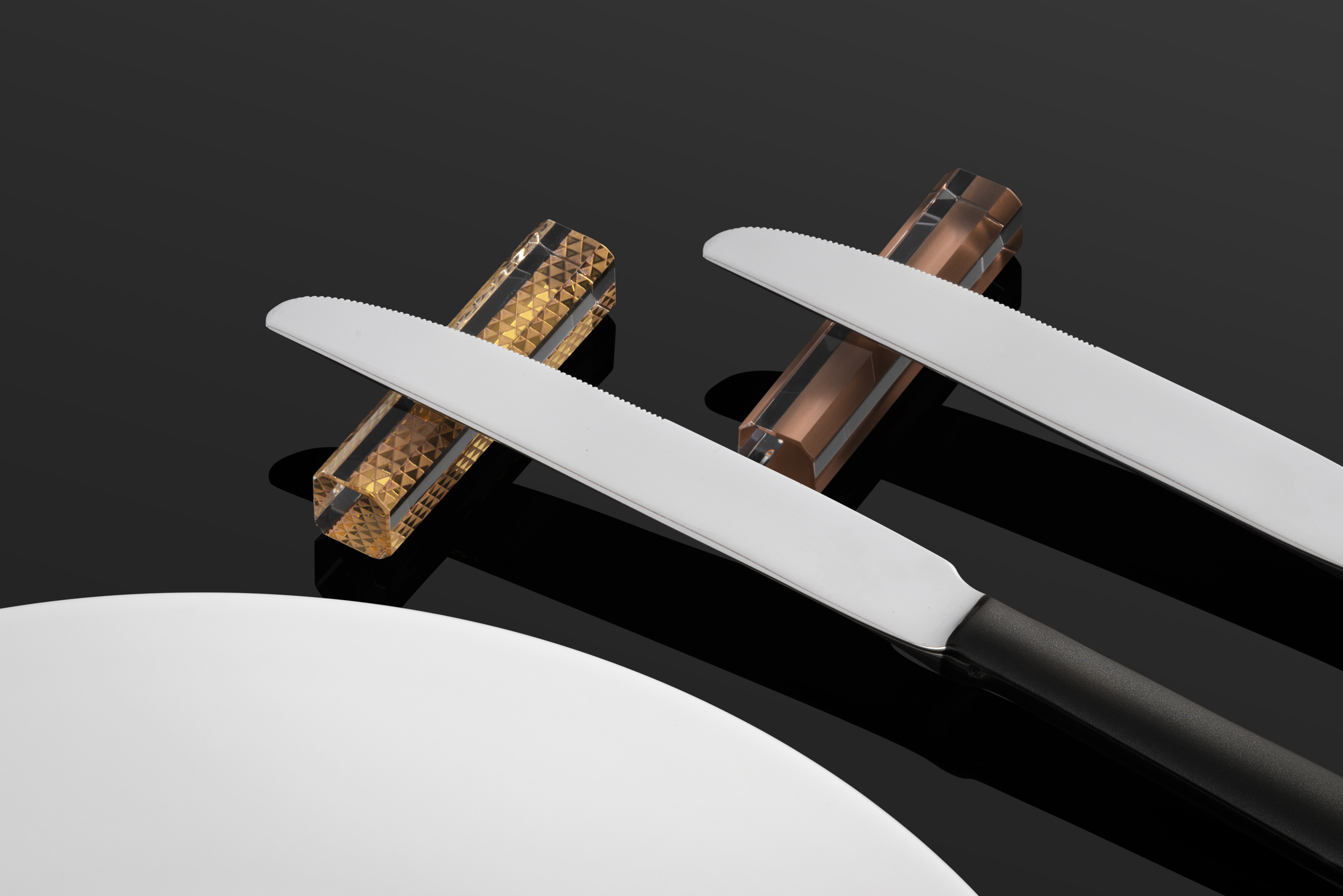 Two knives lie on a golden and a copper-coloured knife rest