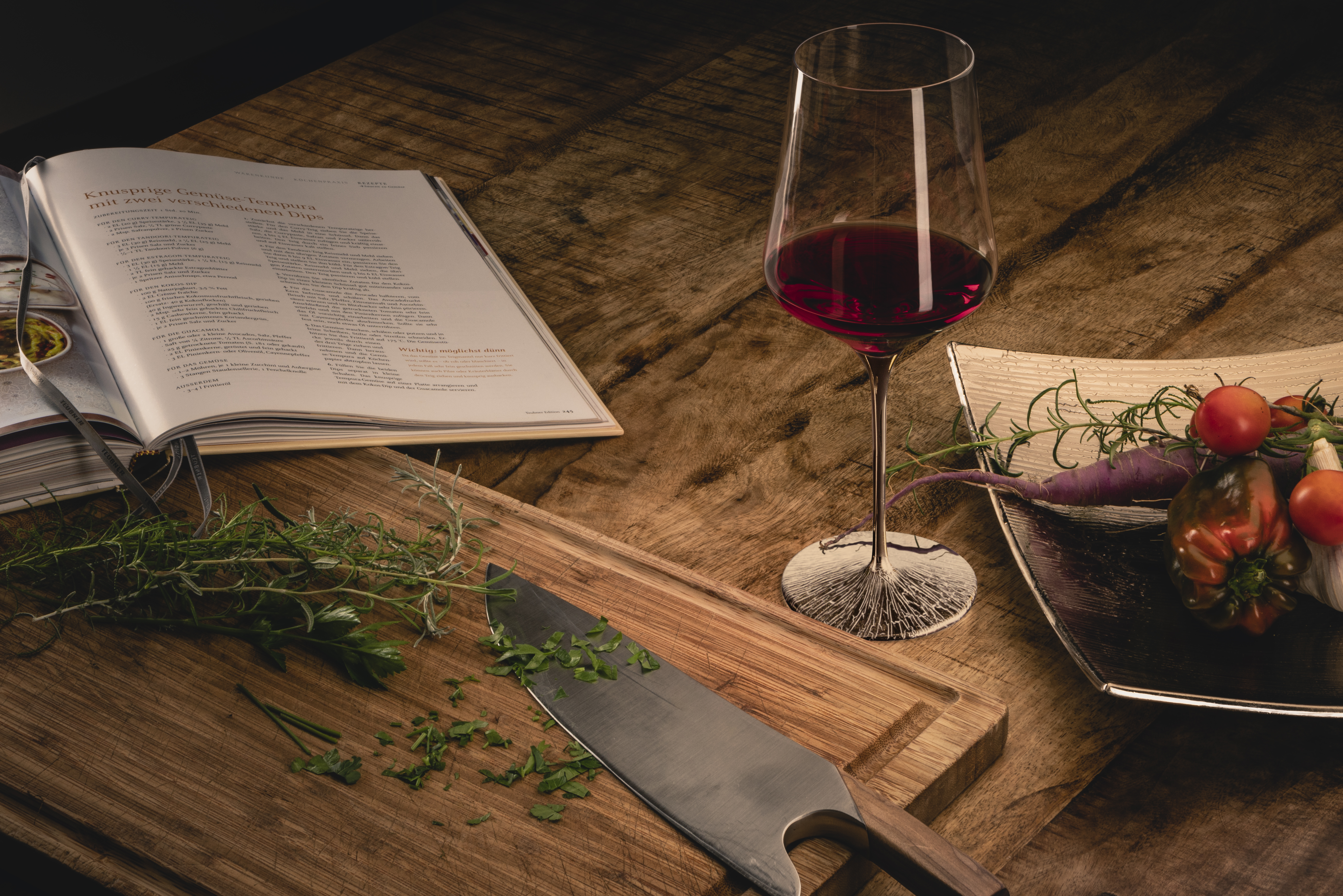 A single wine glass with a platinum stem next to a cookbook