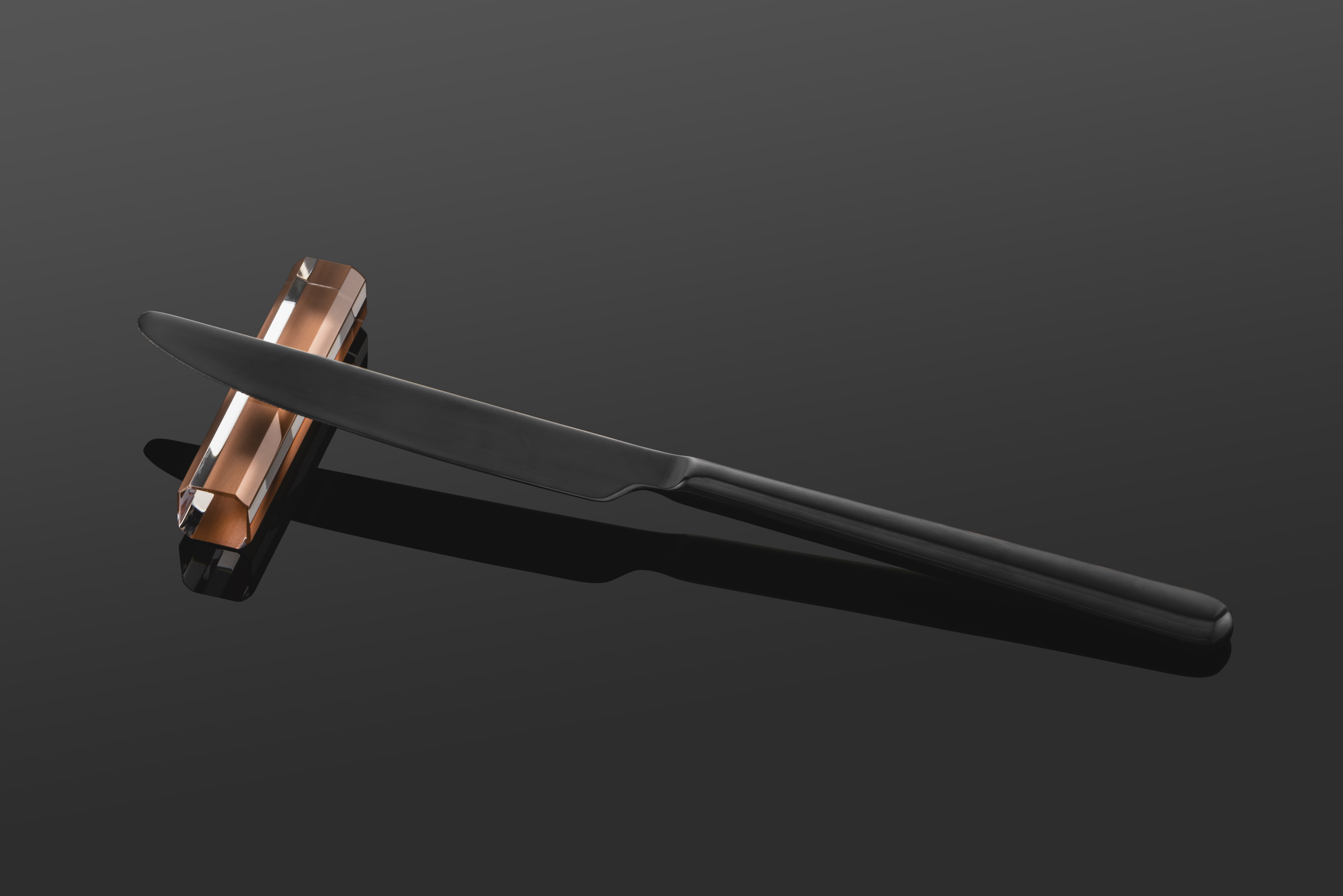 A black knife lies on a copper-coloured knife rest