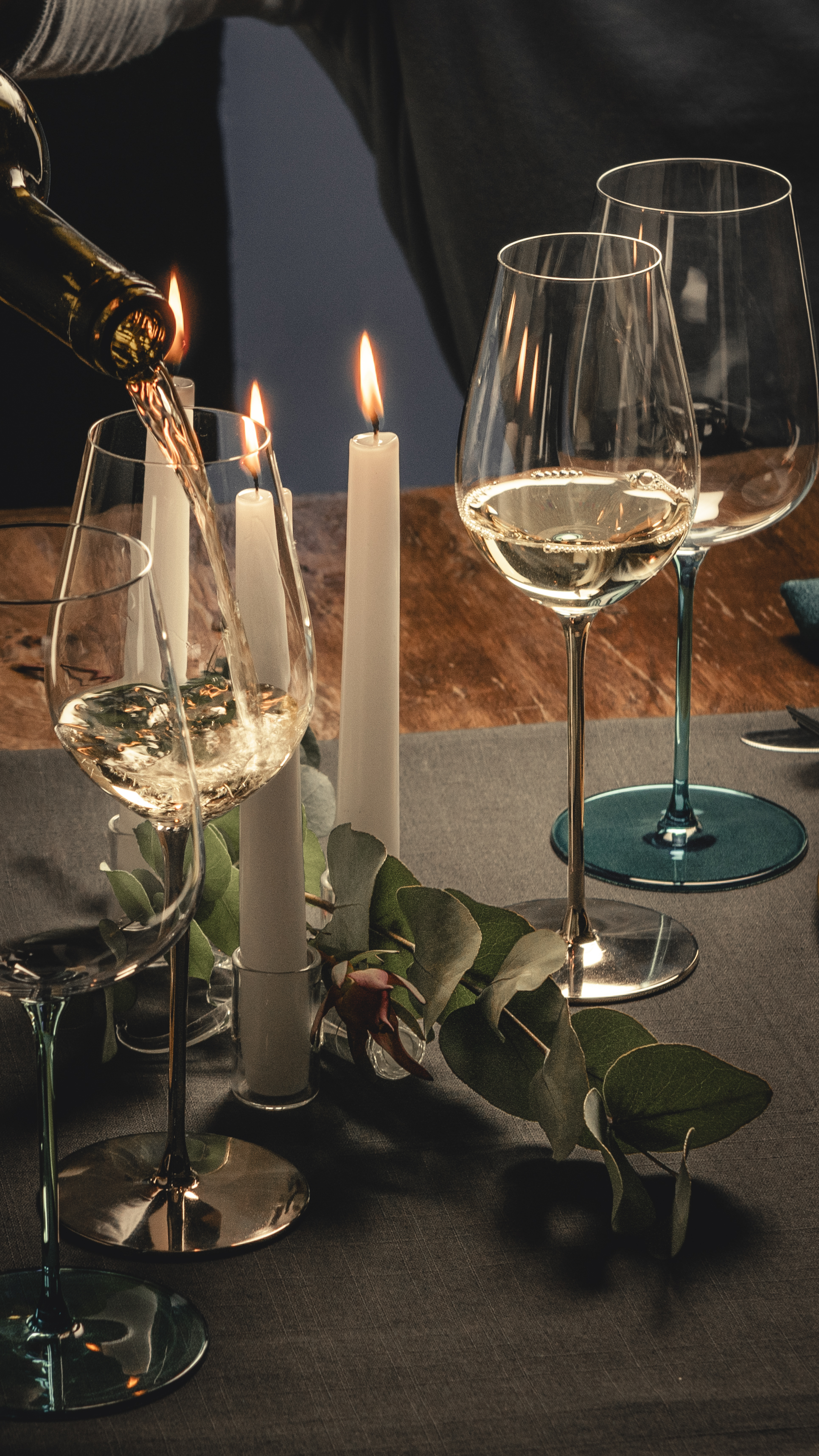 Three white wine glasses with coloured stems on a table