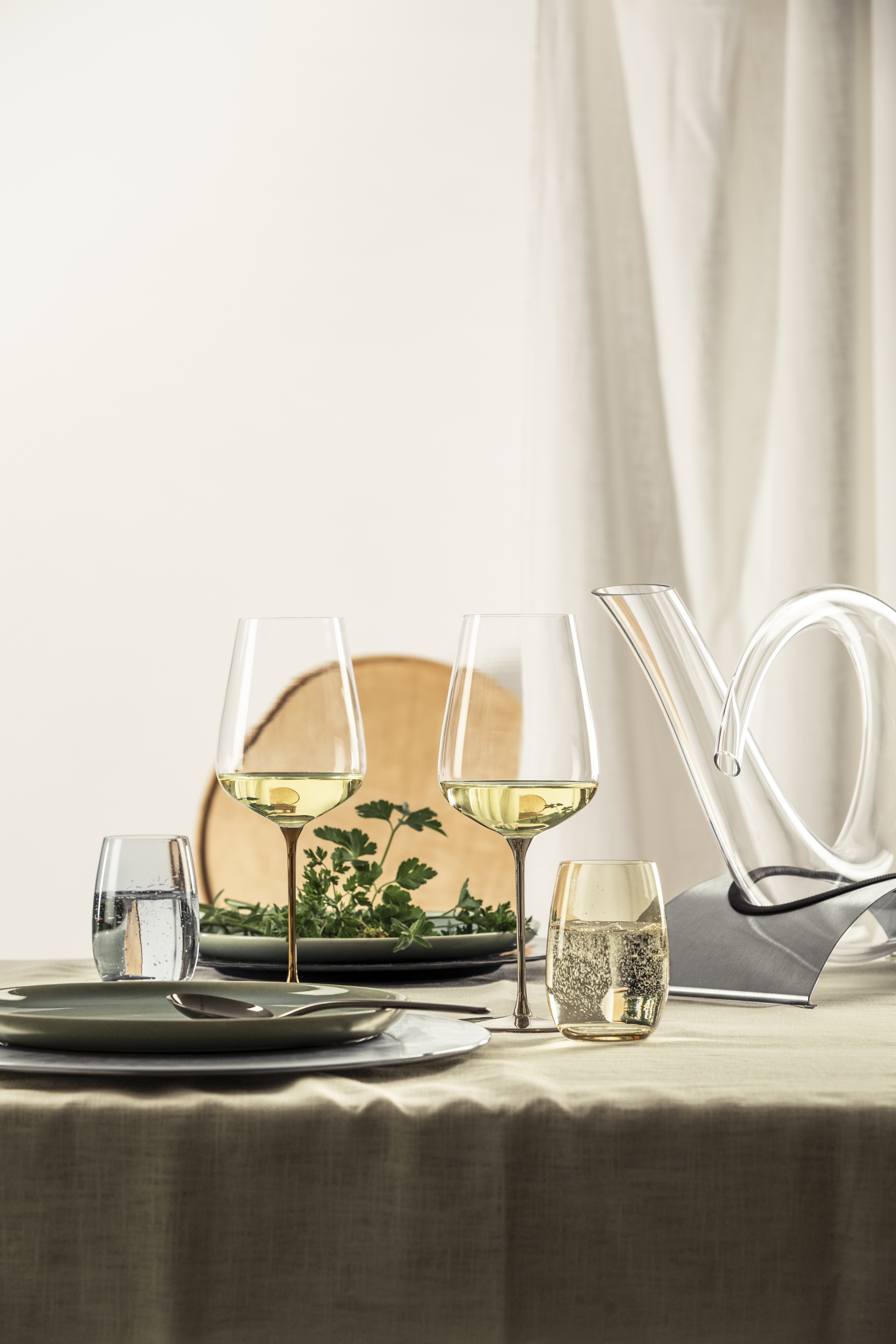 Two white wine glasses with decanter on a set table