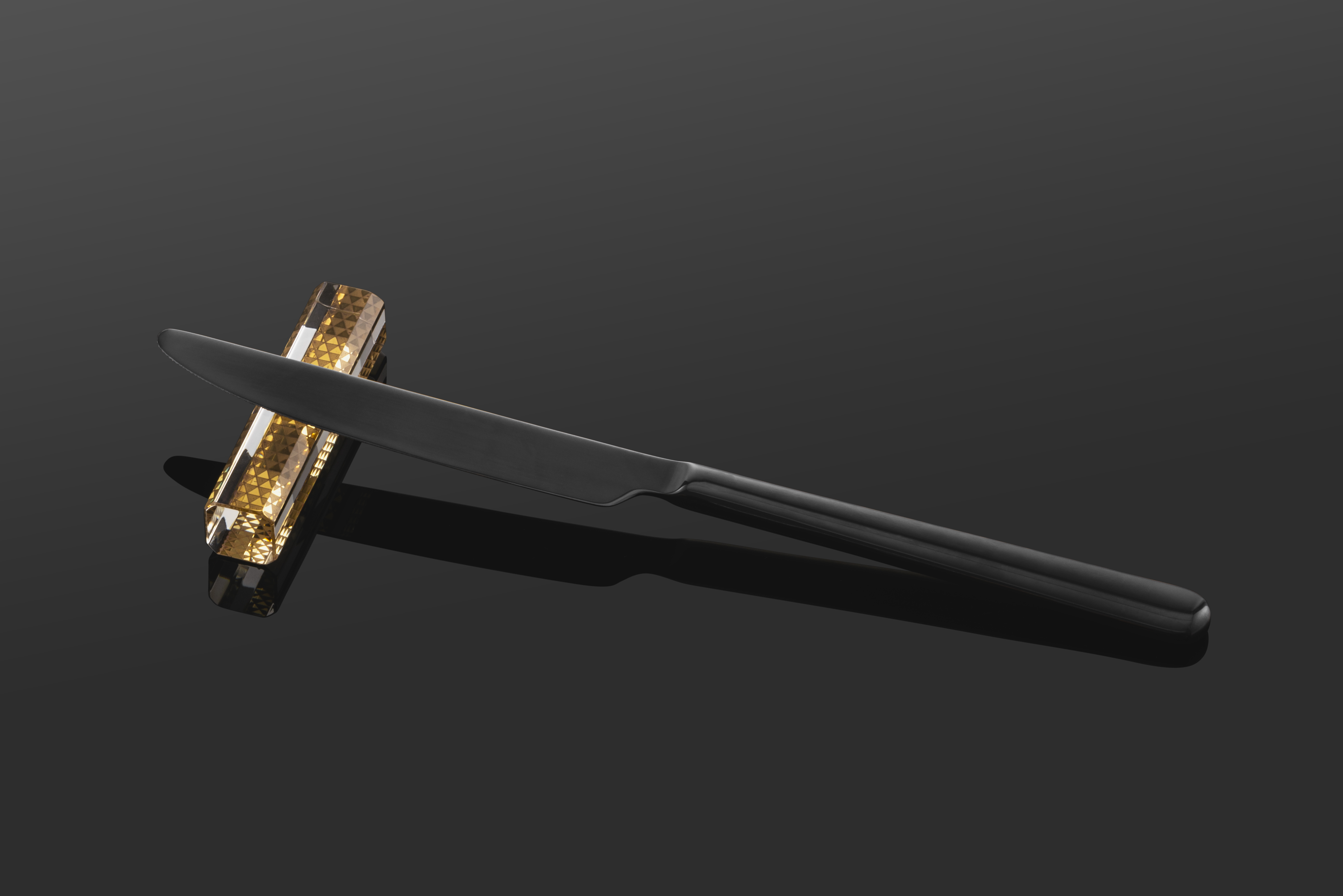 A black knife lies on a golden knife rest