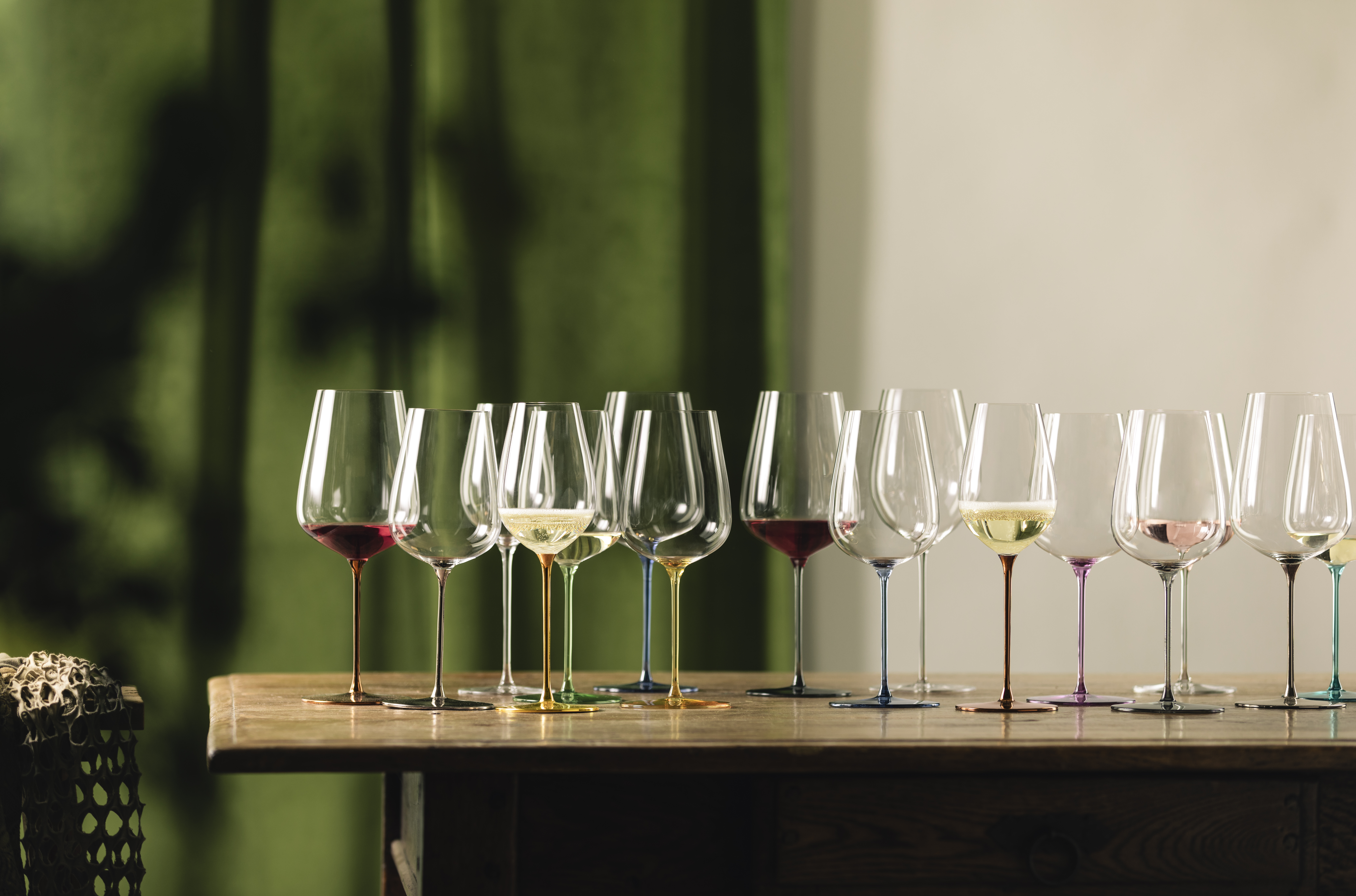 Many colourful wine glasses with contents on a table