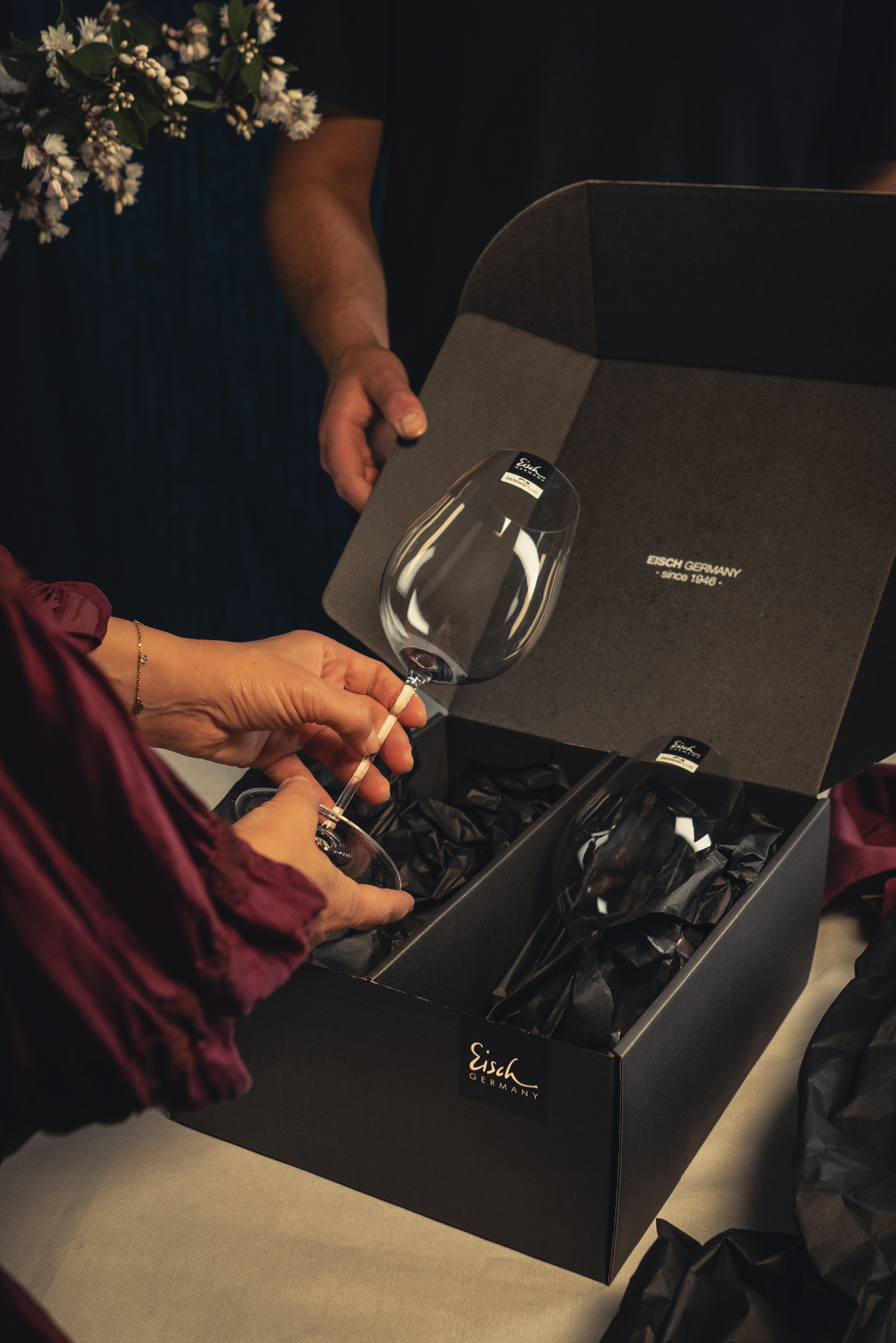 A wine glass is unpacked from a black gift box