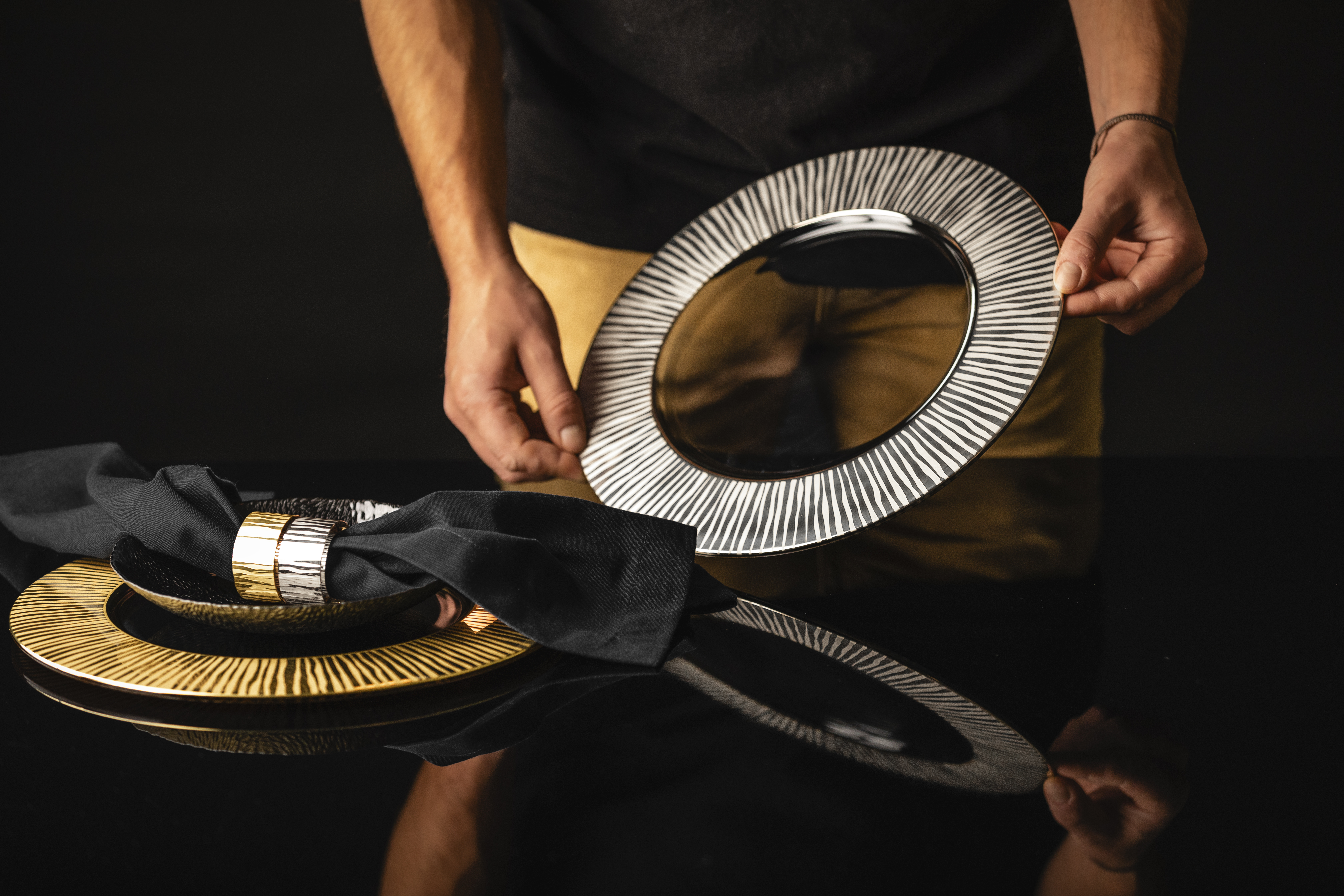 Hände stellen silbernen Teller auf Tisch