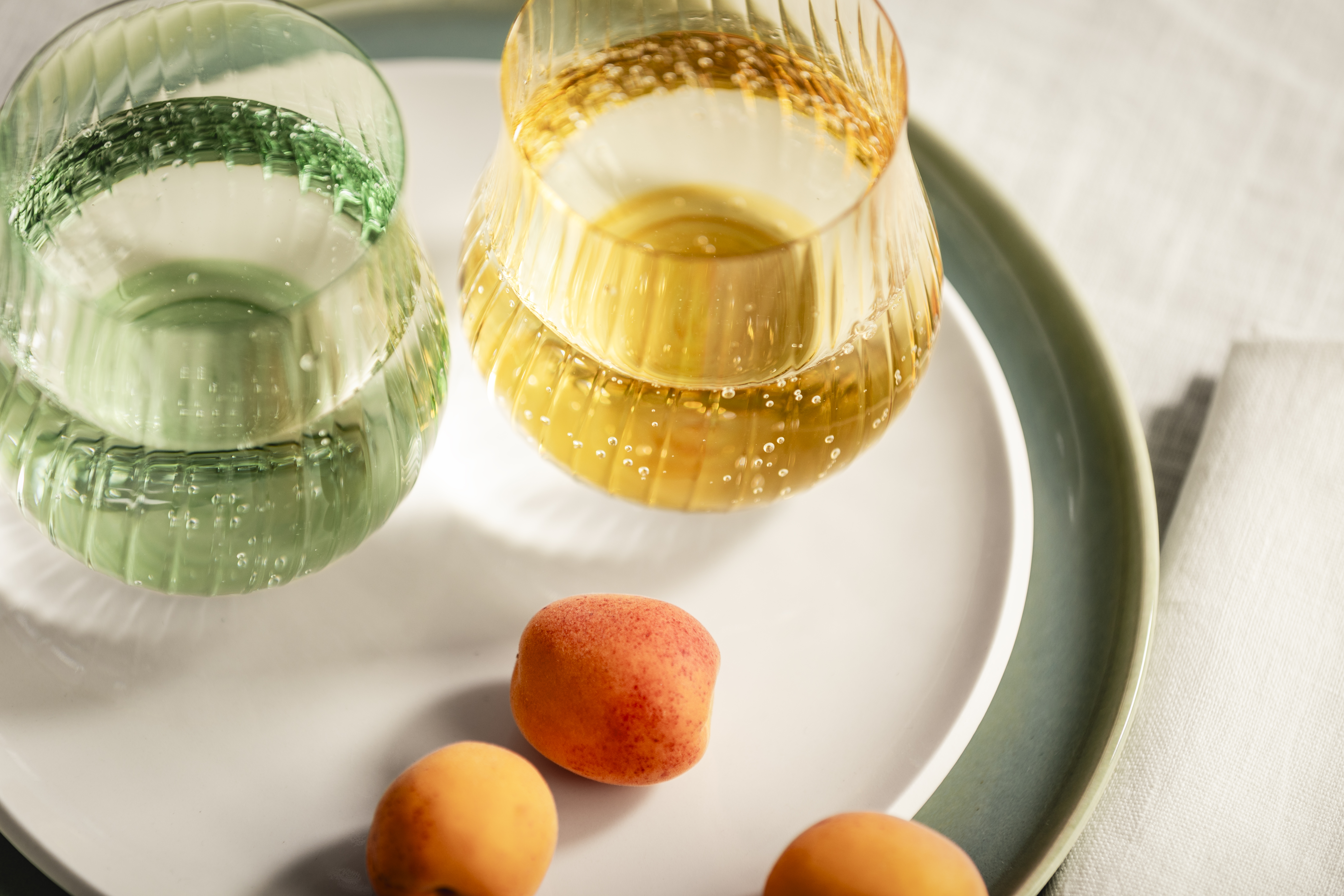 Green and yellow Rising mug next to three apricots