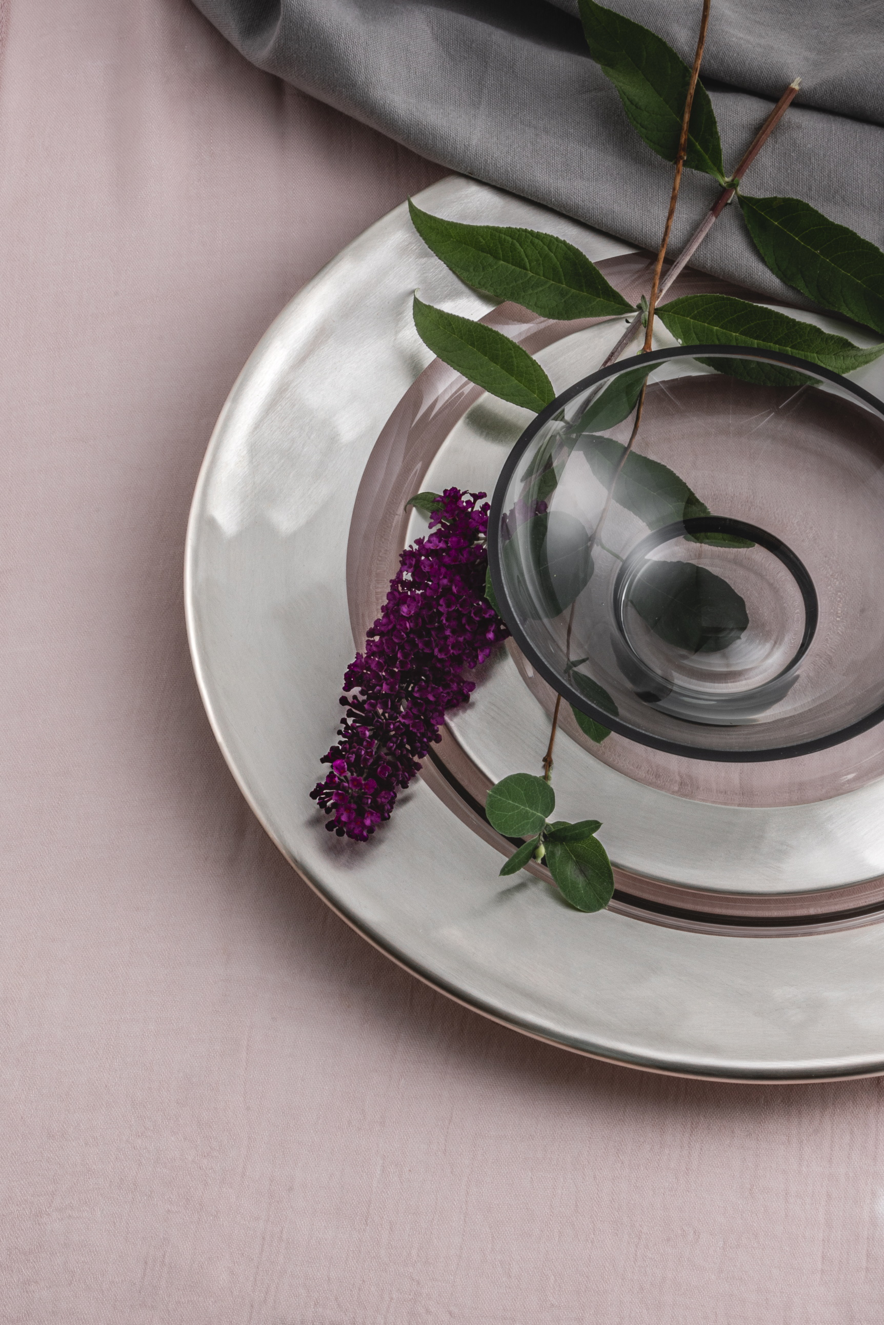 Zwei silberne Teller aufeinander mit einer lila Blüte darauf