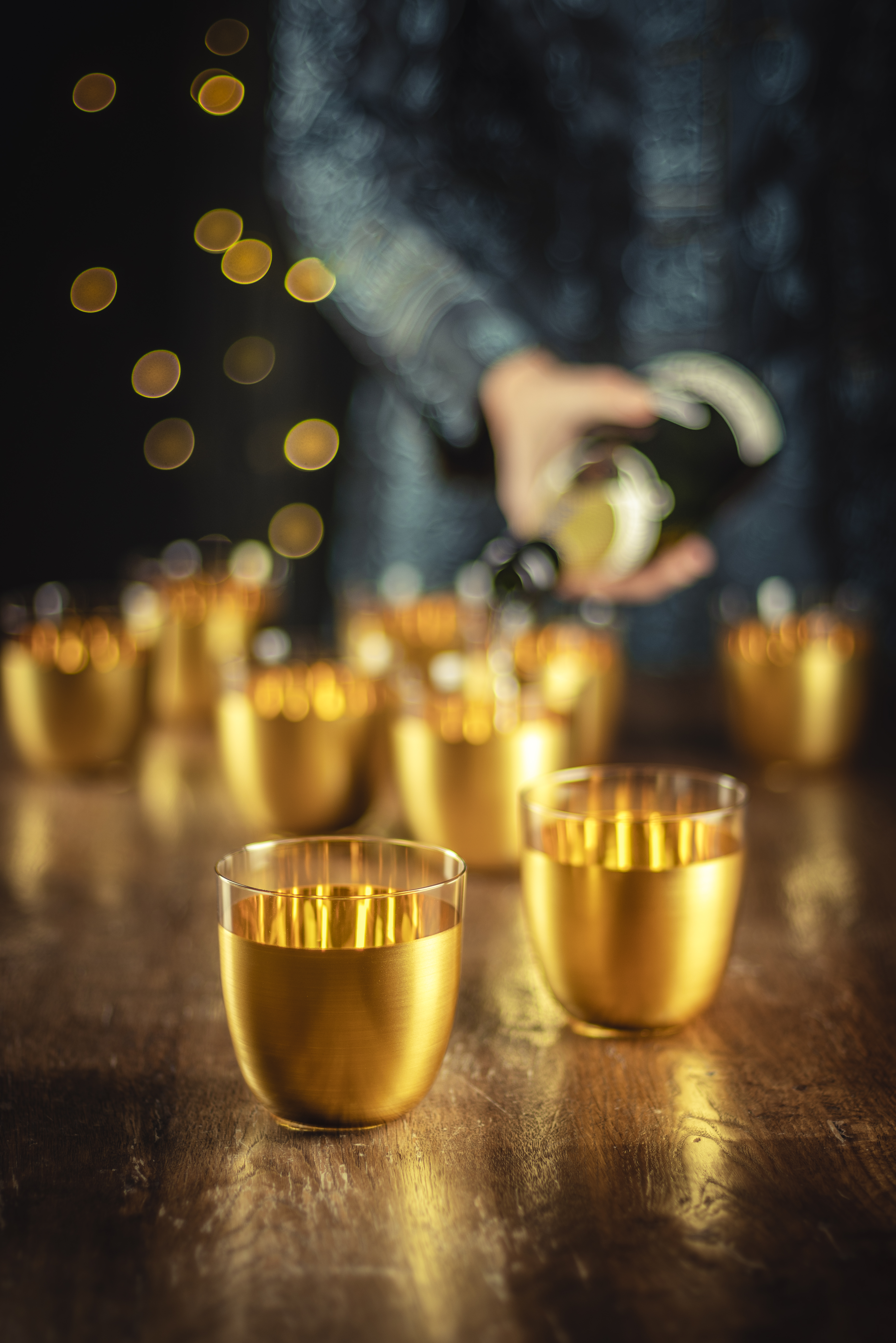 Cosmo Gold cups with champagne bottle in the background