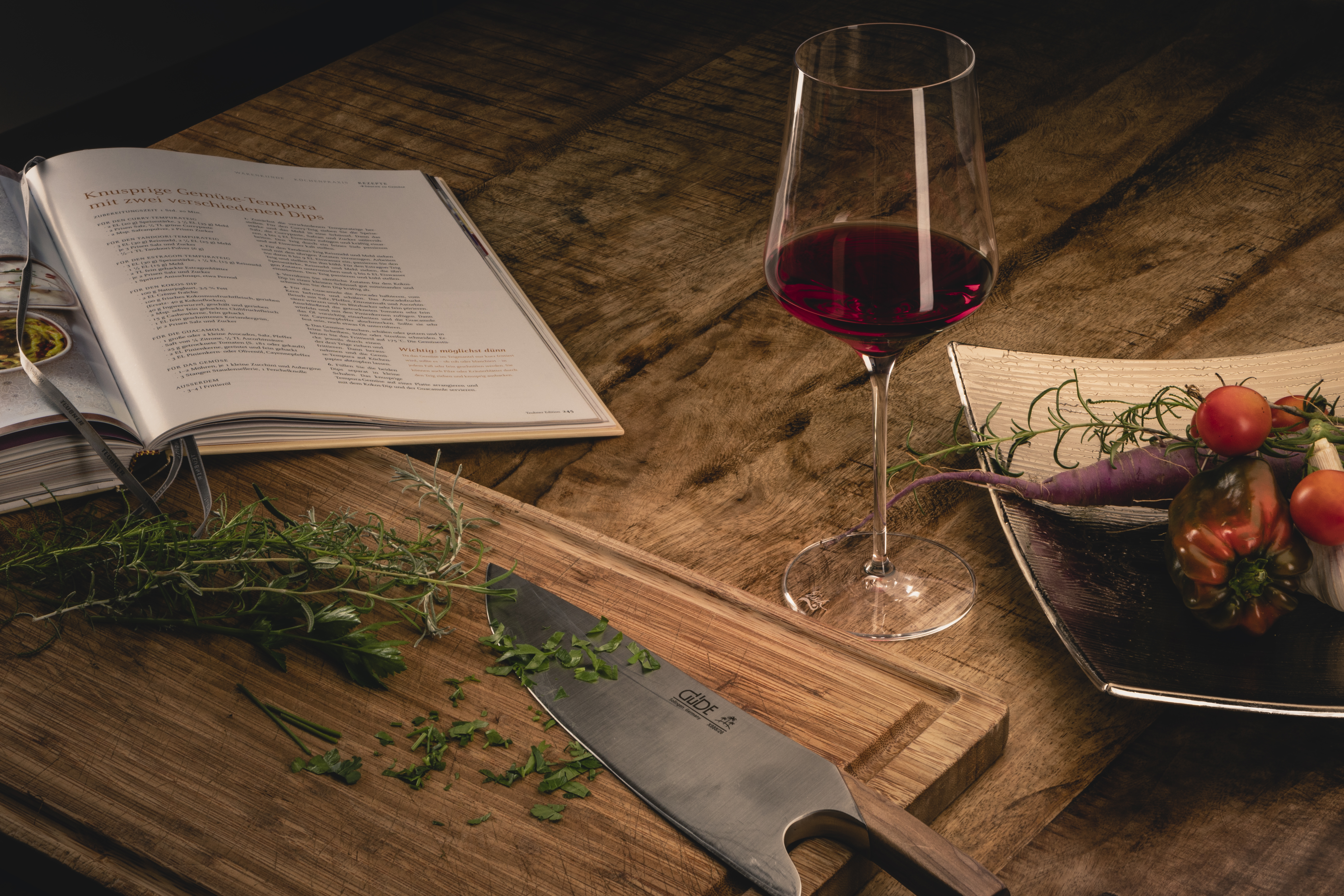 Weinglas zwischen Kochbuch und Schneidebrett