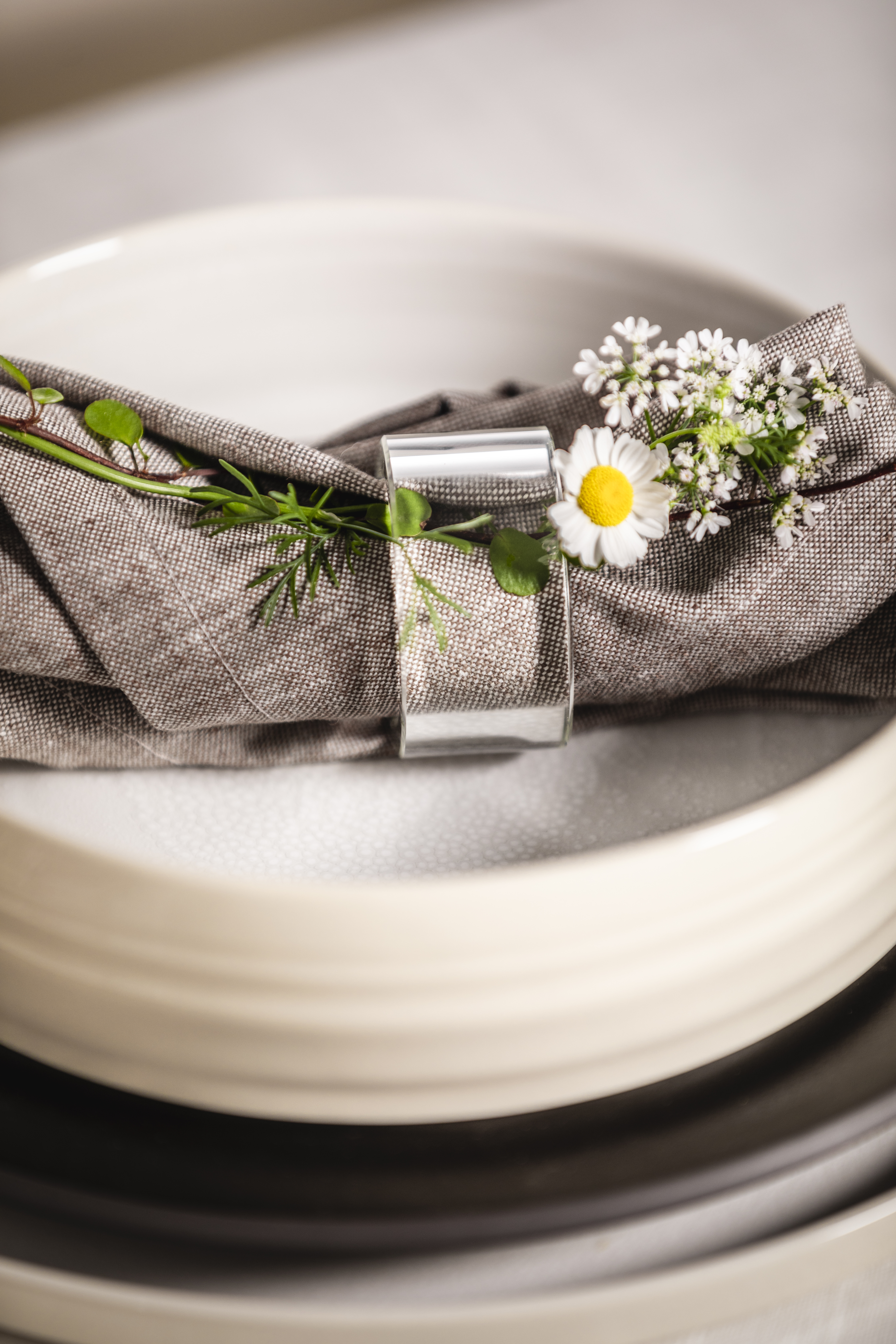 Clear napkin ring with grey napkin and daisies