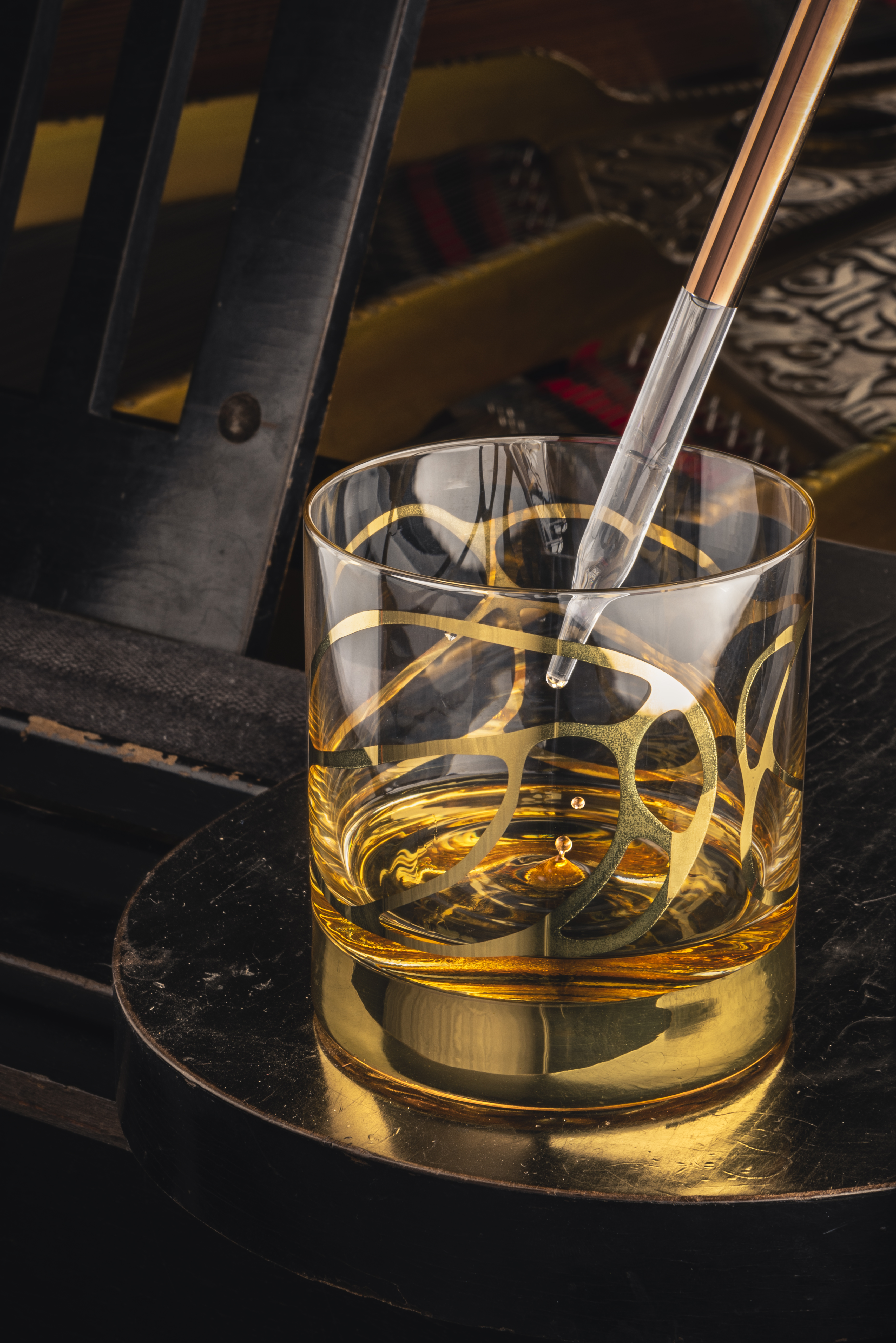 Whisky tumbler with gold pattern and copper pipette